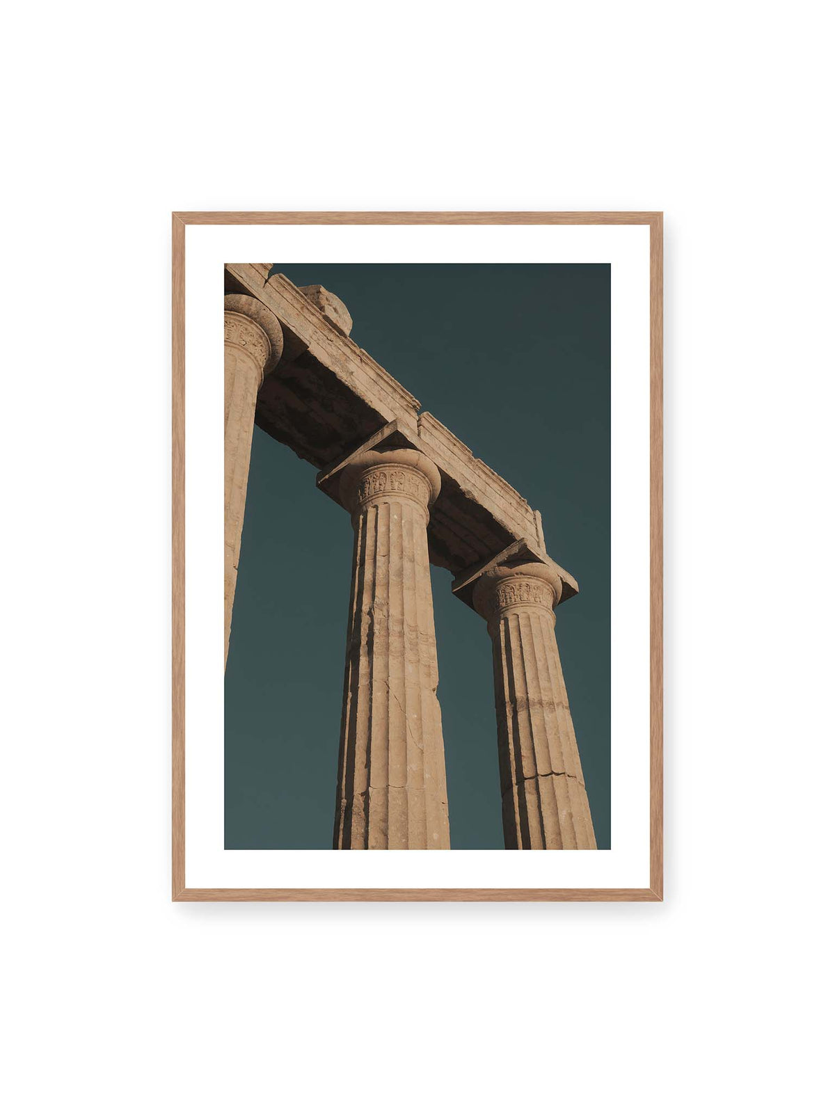 70x100 cm, weißer Galerie-Rand, Eichenrahmen – Monumentale Steinsäulen mit verzierten Kapitellen und verwittertem Gebälk vor dunklem Himmel.