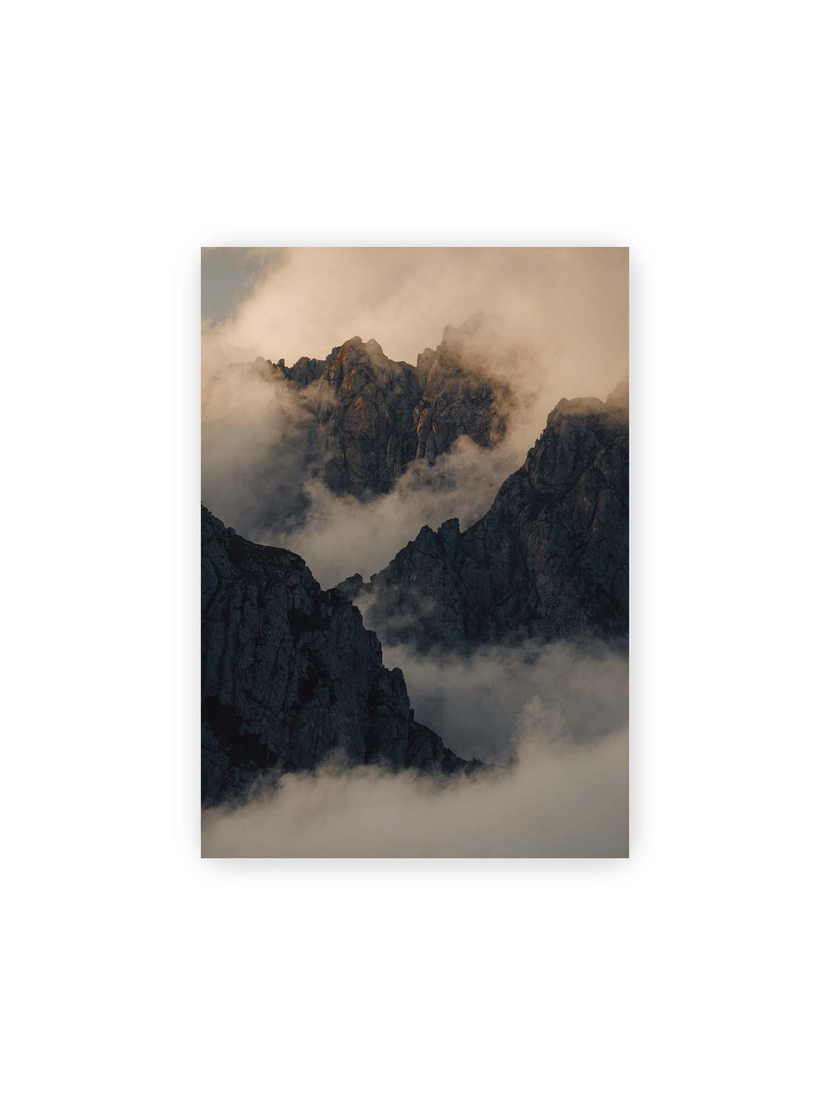 21x30 cm – Zerklüftete dunkle Bergspitzen zwischen dichten Wolken mit warm beleuchteten Felsflächen.