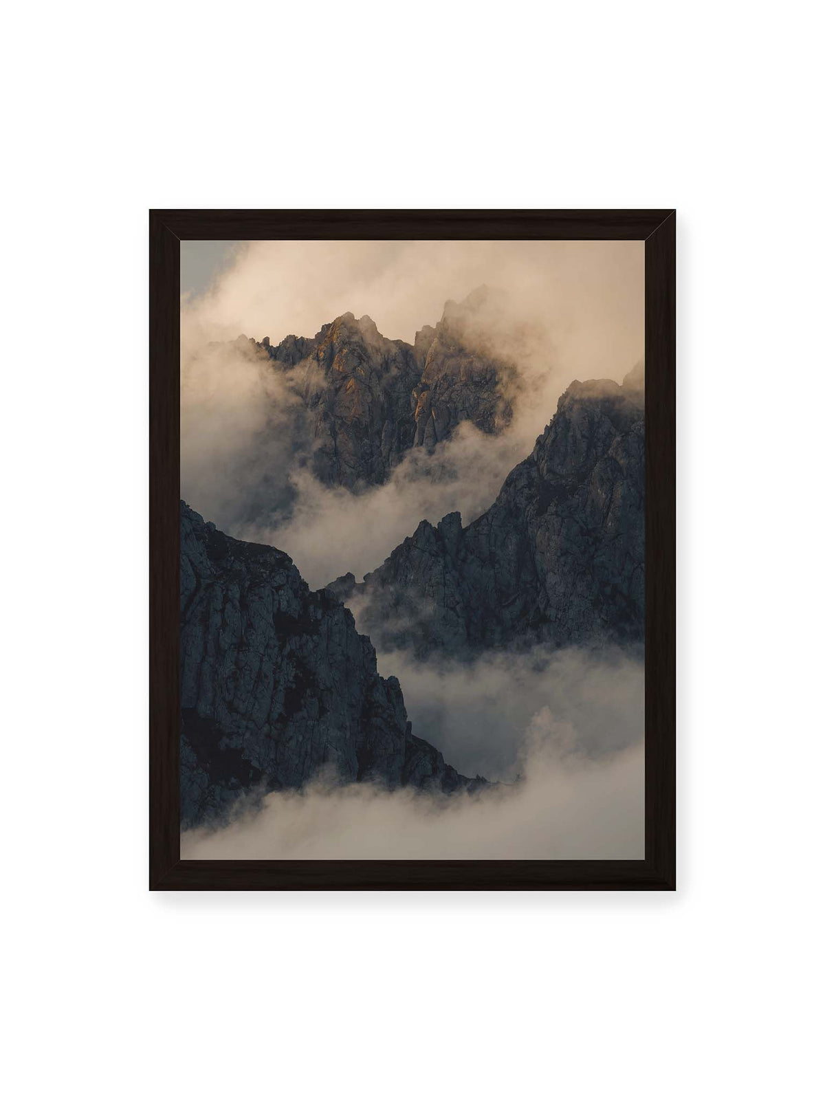30x40 cm, schwarzer Rahmen – Zerklüftete dunkle Bergspitzen zwischen dichten Wolken mit warm beleuchteten Felsflächen.