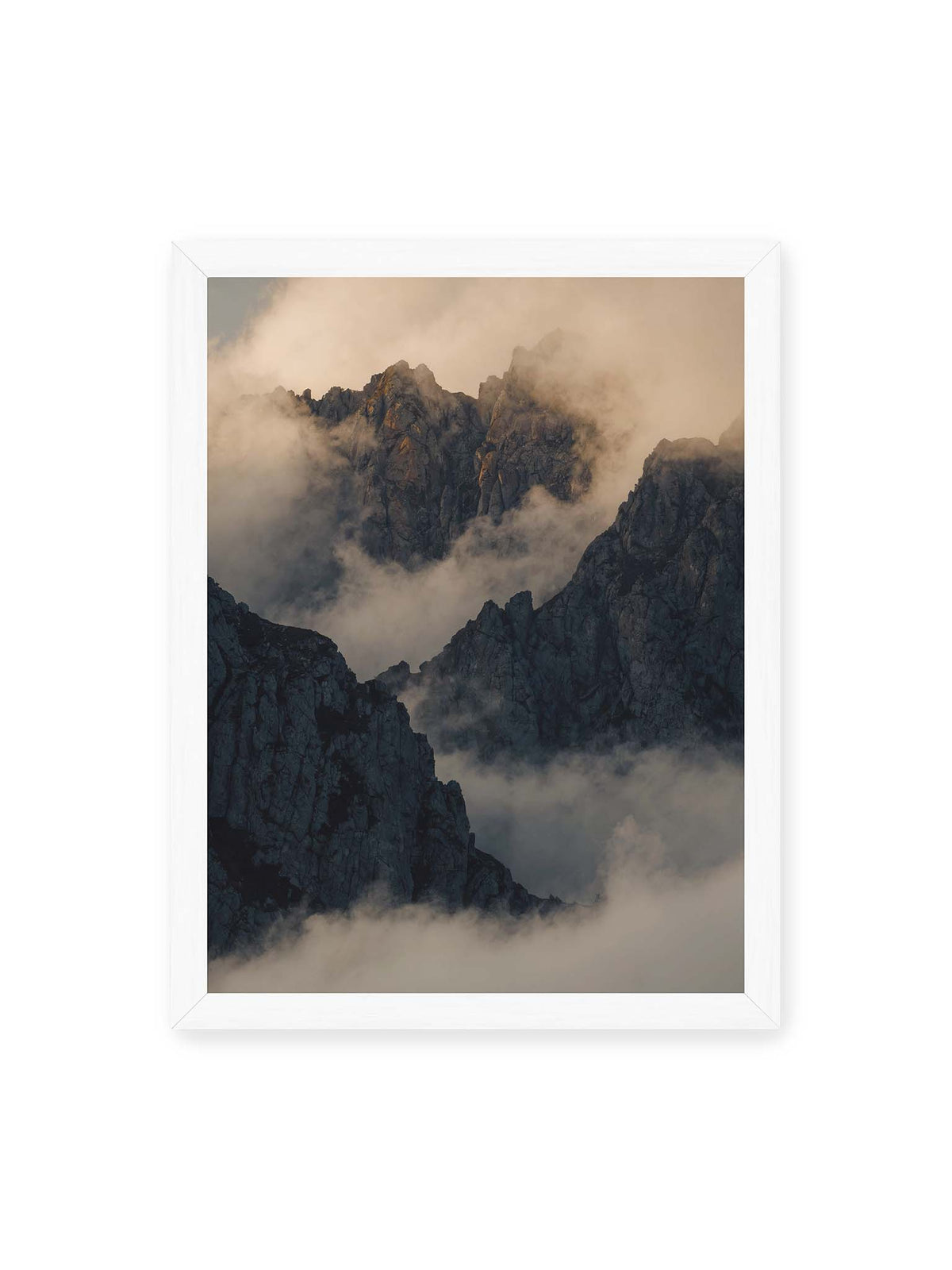 30x40 cm, weißer Rahmen – Zerklüftete dunkle Bergspitzen zwischen dichten Wolken mit warm beleuchteten Felsflächen.