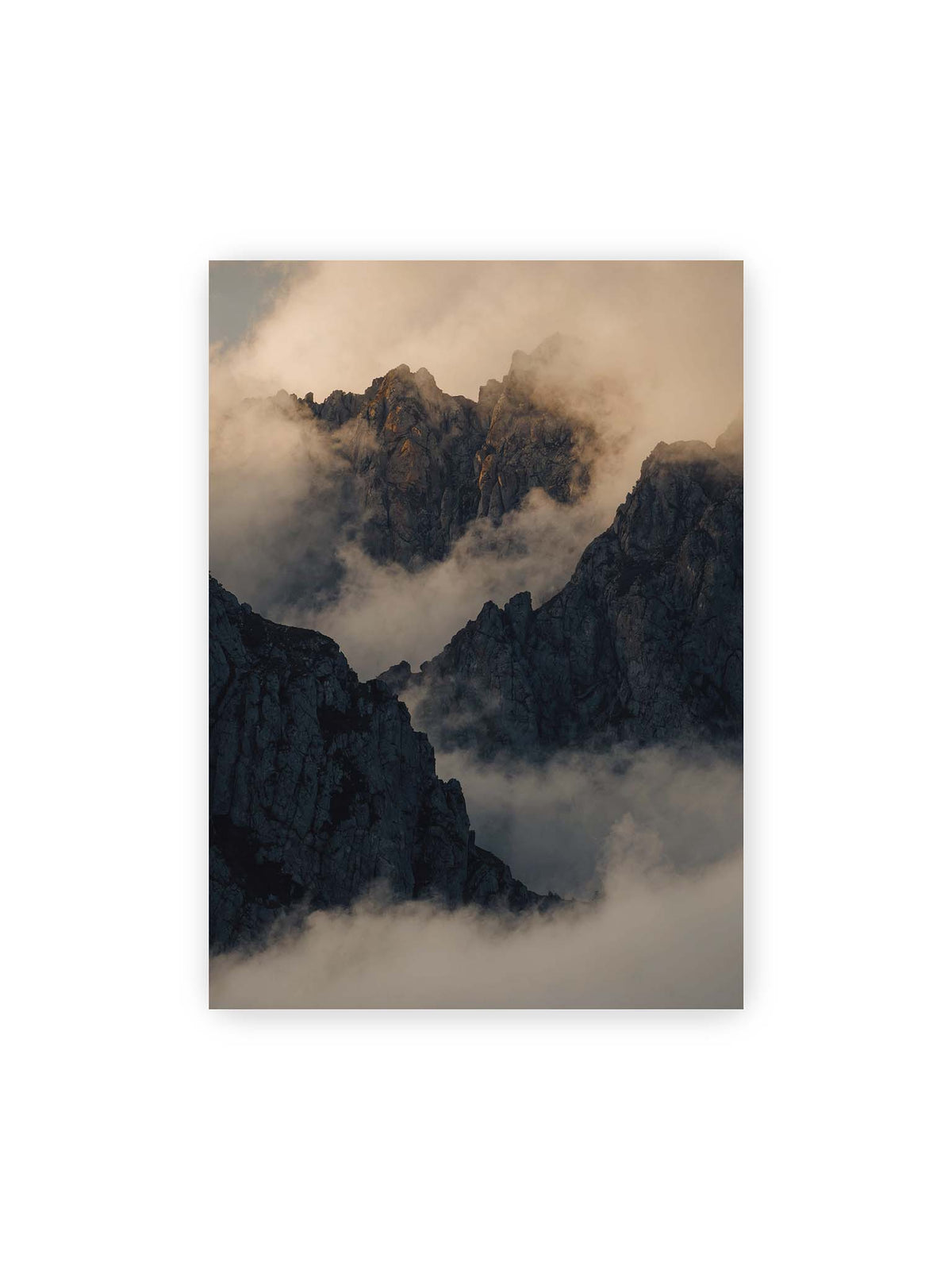 50x70 cm – Zerklüftete dunkle Bergspitzen zwischen dichten Wolken mit warm beleuchteten Felsflächen.