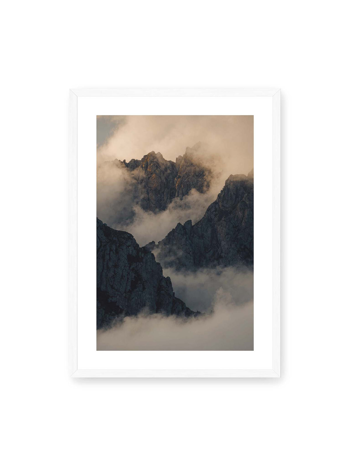 50x70 cm, weißer Galerie-Rand, weißer Rahmen – Zerklüftete dunkle Bergspitzen zwischen dichten Wolken mit warm beleuchteten Felsflächen.