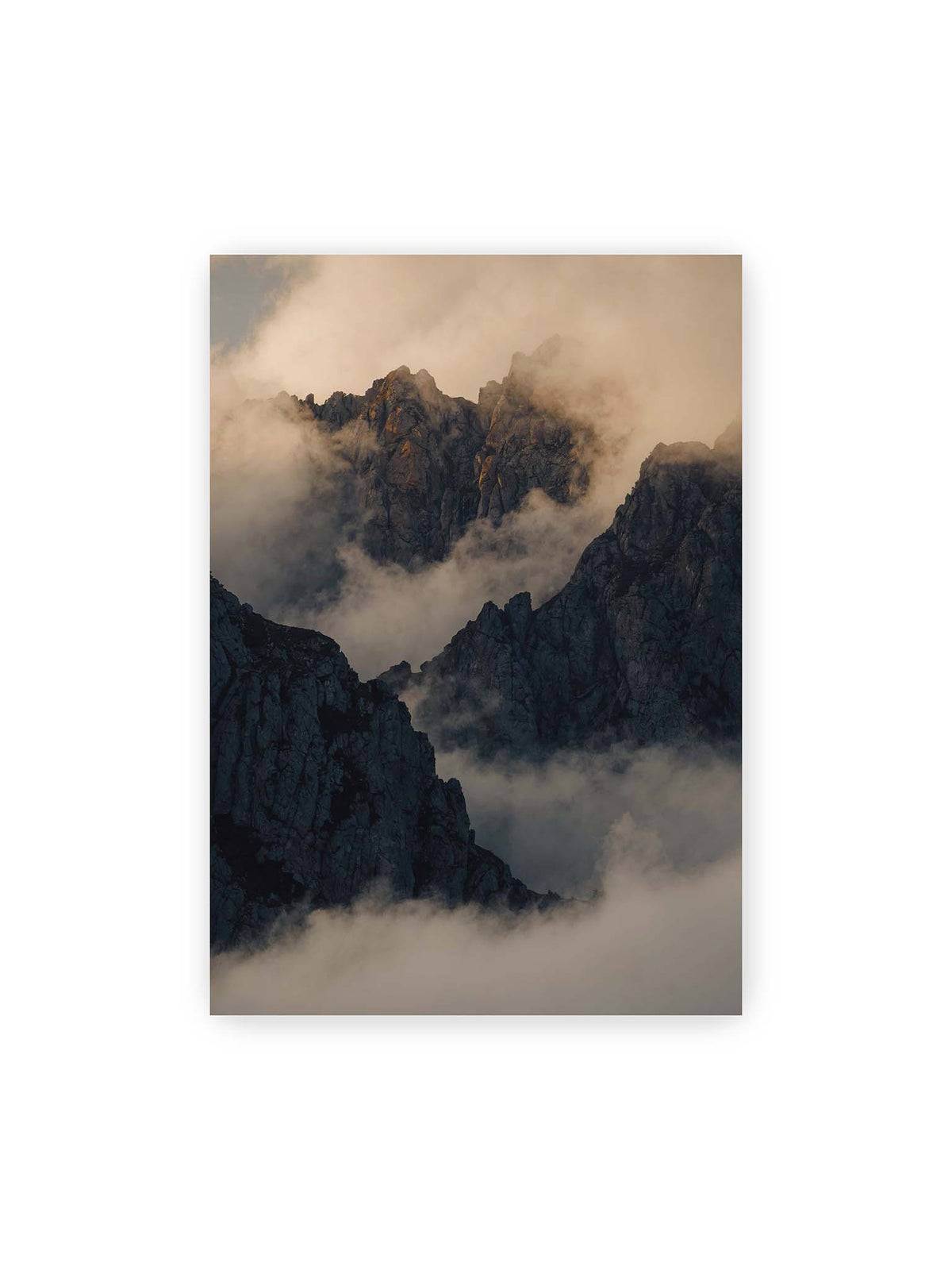 70x100 cm – Zerklüftete dunkle Bergspitzen zwischen dichten Wolken mit warm beleuchteten Felsflächen.