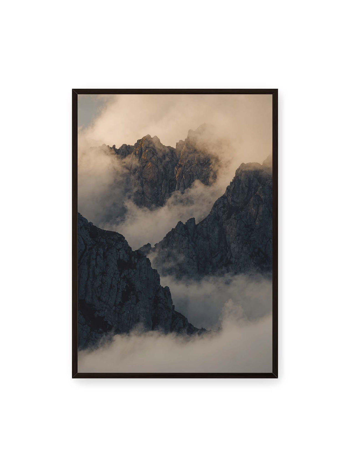 70x100 cm, schwarzer Rahmen – Zerklüftete dunkle Bergspitzen zwischen dichten Wolken mit warm beleuchteten Felsflächen.