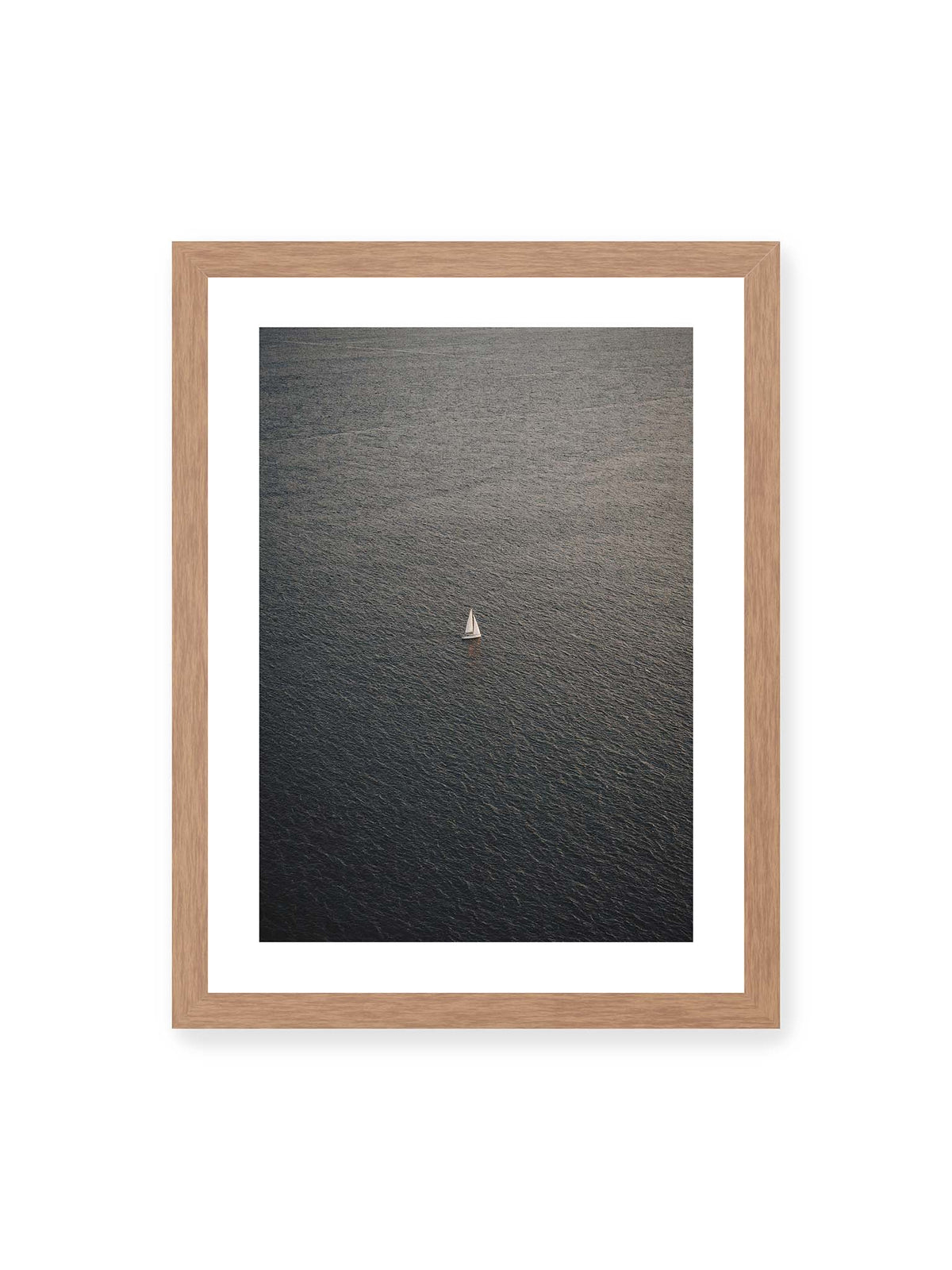 30x40 cm, weißer Galerie-Rand, Eichenrahmen – Einzelnes weißes Segelboot auf einer weitläufigen, dunkel strukturierten Wasserfläche aus erhöhter Perspektive.