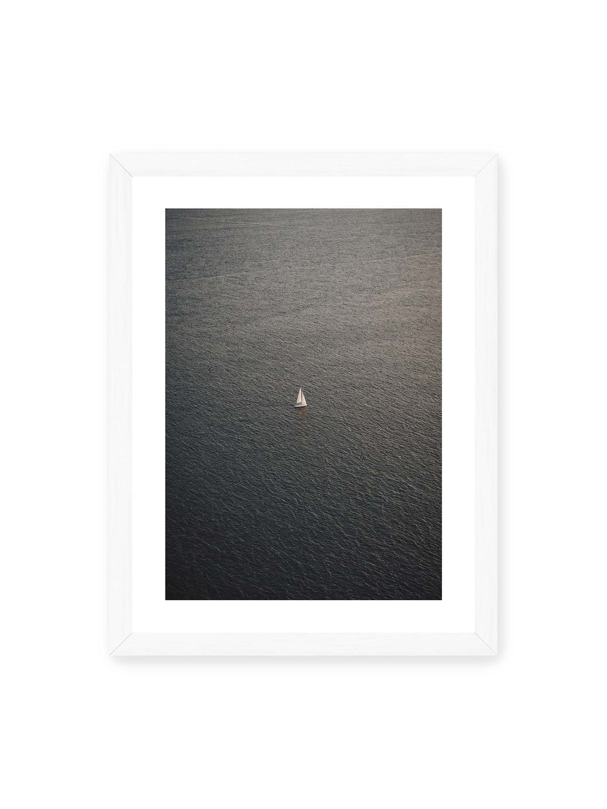 30x40 cm, weißer Galerie-Rand, weißer Rahmen – Einzelnes weißes Segelboot auf einer weitläufigen, dunkel strukturierten Wasserfläche aus erhöhter Perspektive.
