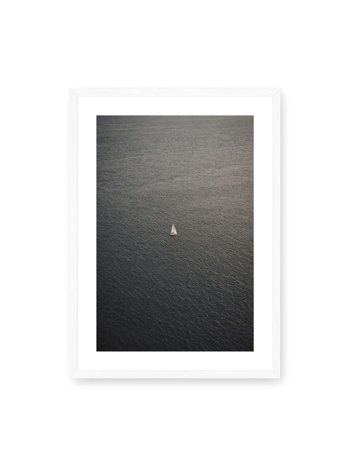 50x70 cm, weißer Galerie-Rand, weißer Rahmen – Einzelnes weißes Segelboot auf einer weitläufigen, dunkel strukturierten Wasserfläche aus erhöhter Perspektive.