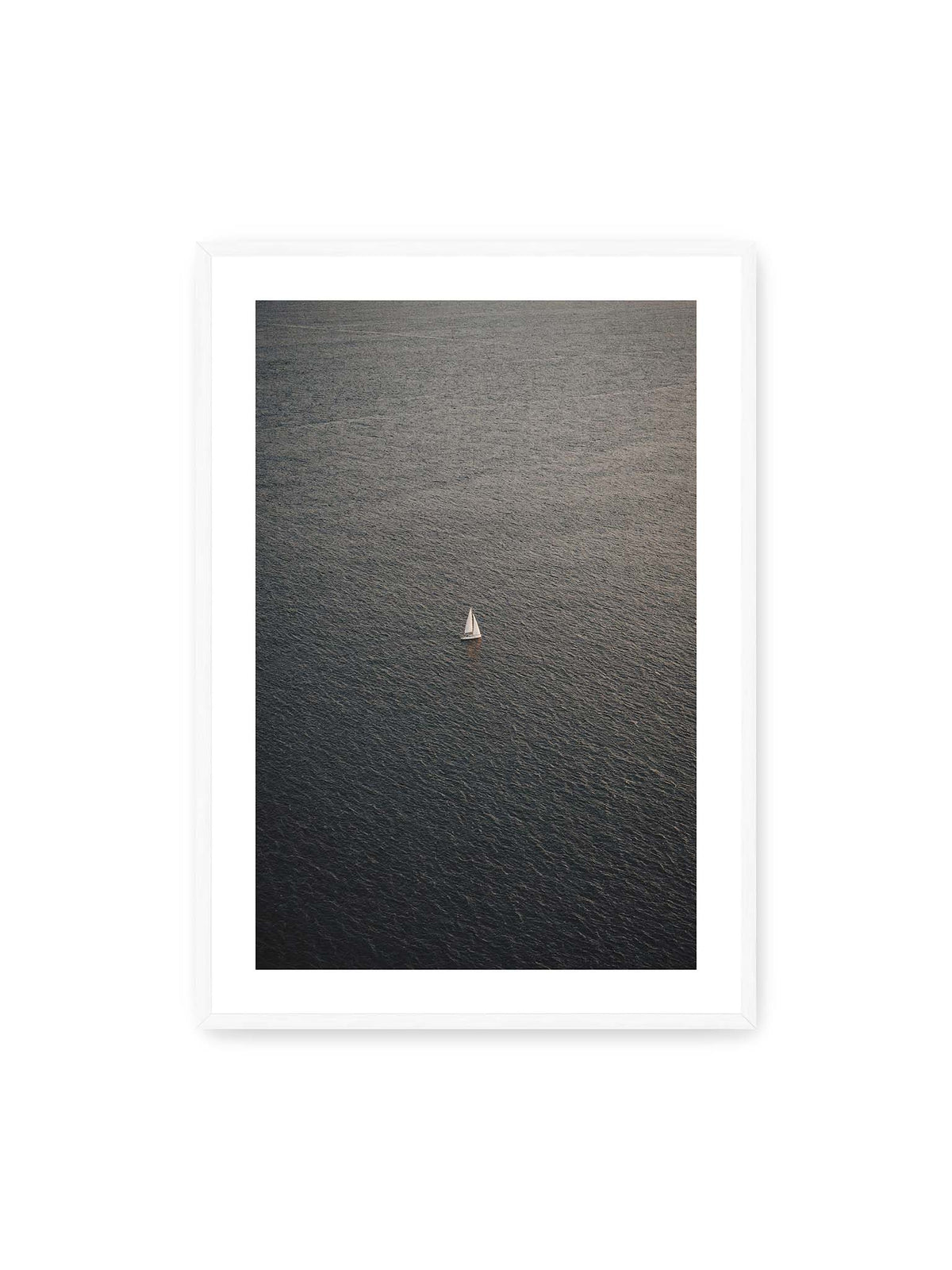 70x100 cm, weißer Galerie-Rand, weißer Rahmen – Einzelnes weißes Segelboot auf einer weitläufigen, dunkel strukturierten Wasserfläche aus erhöhter Perspektive.
