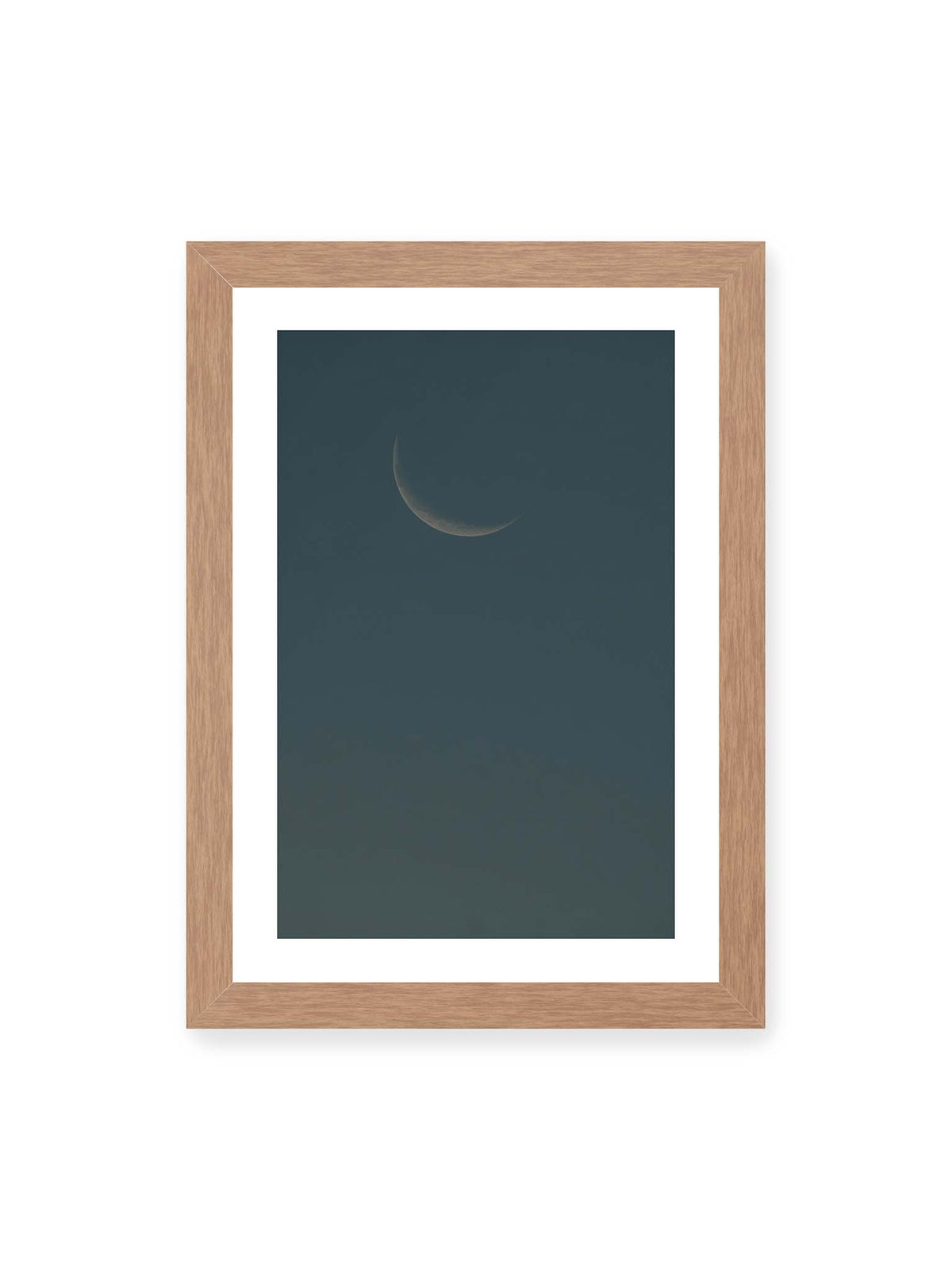 21x30 cm, weißer Galerie-Rand, Eichenrahmen – Schmale Mondsichel mit feiner Oberflächenstruktur vor einer weitläufigen dunkelblauen Himmelsfläche.