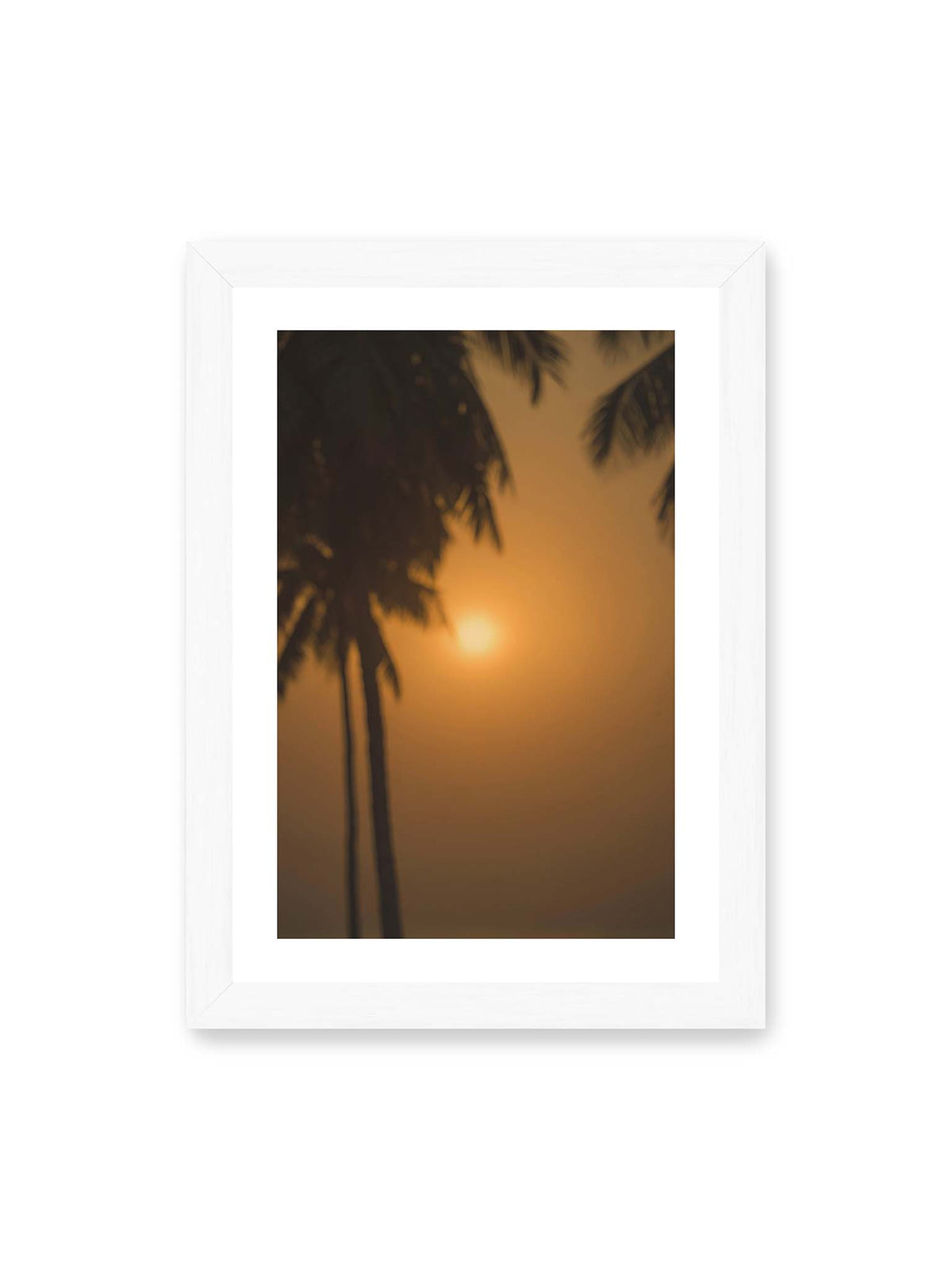 21x30 cm, weißer Galerie-Rand, weißer Rahmen – Unscharfe dunkle Palmen vor goldenem Himmel mit einer hell leuchtenden Sonne zwischen den Silhouetten.