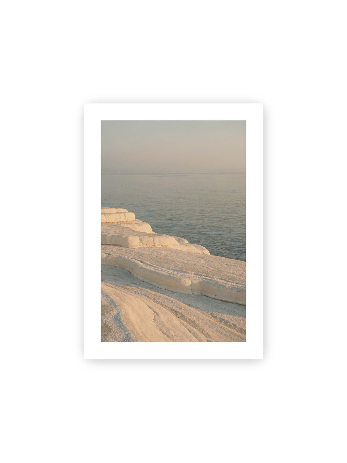 21x30 cm, weißer Galerie-Rand – Helle terrassenartige Gesteinsflächen fallen in sanften Stufen zu einem ruhigen, blassblauen Meer ab.