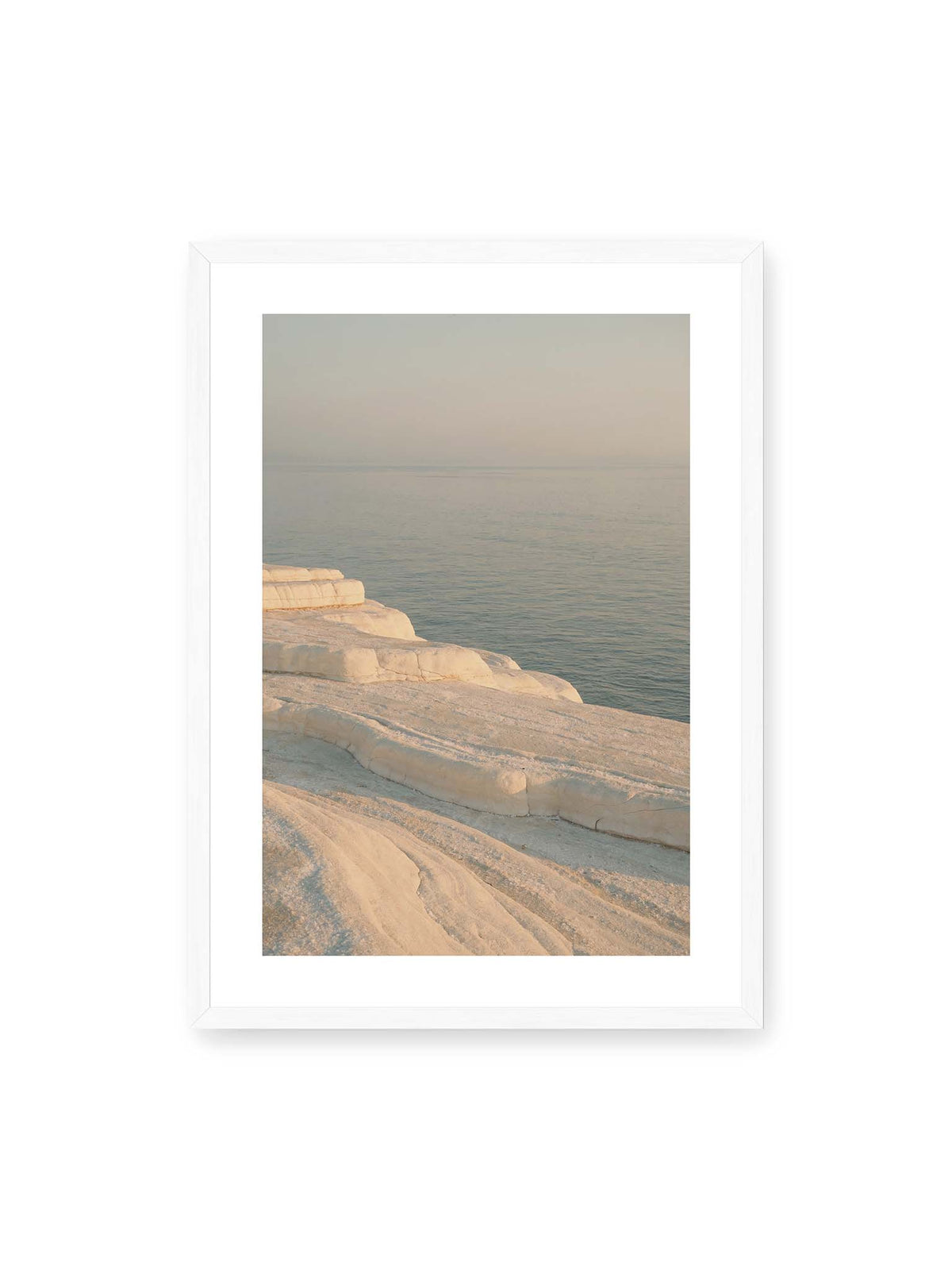 50x70 cm, weißer Galerie-Rand, weißer Rahmen – Helle terrassenartige Gesteinsflächen fallen in sanften Stufen zu einem ruhigen, blassblauen Meer ab.