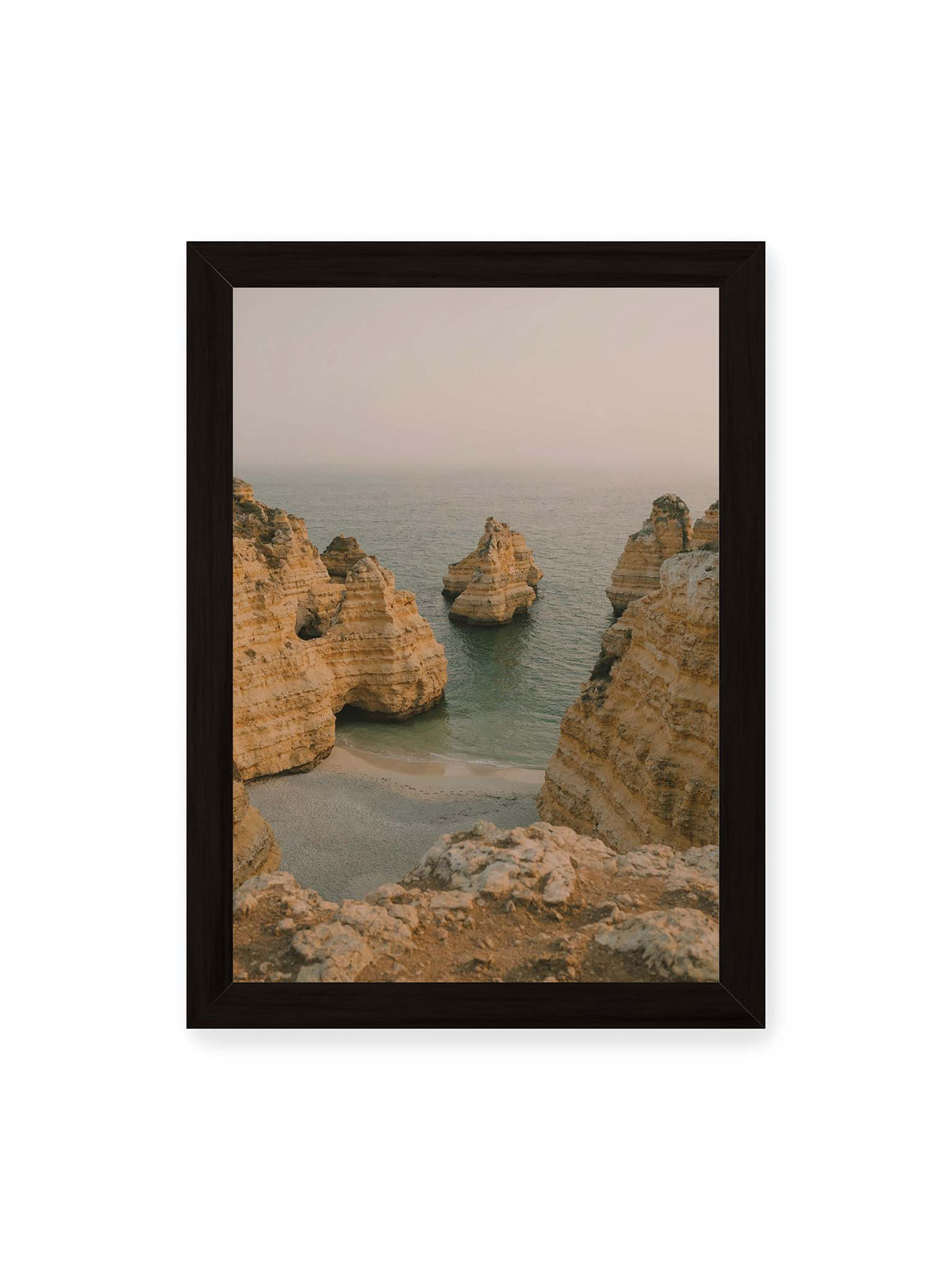 21x30 cm, schwarzer Rahmen – Schichtartige Felsformationen umgeben eine kleine Bucht mit ruhigem Wasser und schmalem Sandstrand.