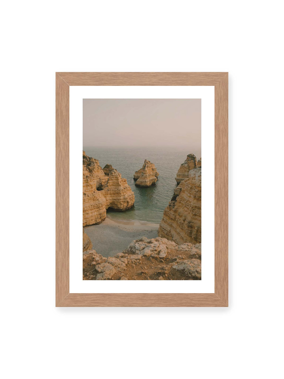 21x30 cm, weißer Galerie-Rand, Eichenrahmen – Schichtartige Felsformationen umgeben eine kleine Bucht mit ruhigem Wasser und schmalem Sandstrand.