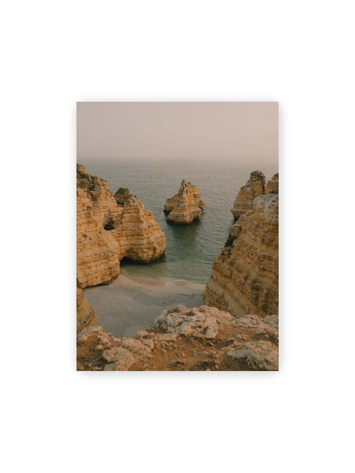 30x40 cm – Schichtartige Felsformationen umgeben eine kleine Bucht mit ruhigem Wasser und schmalem Sandstrand.