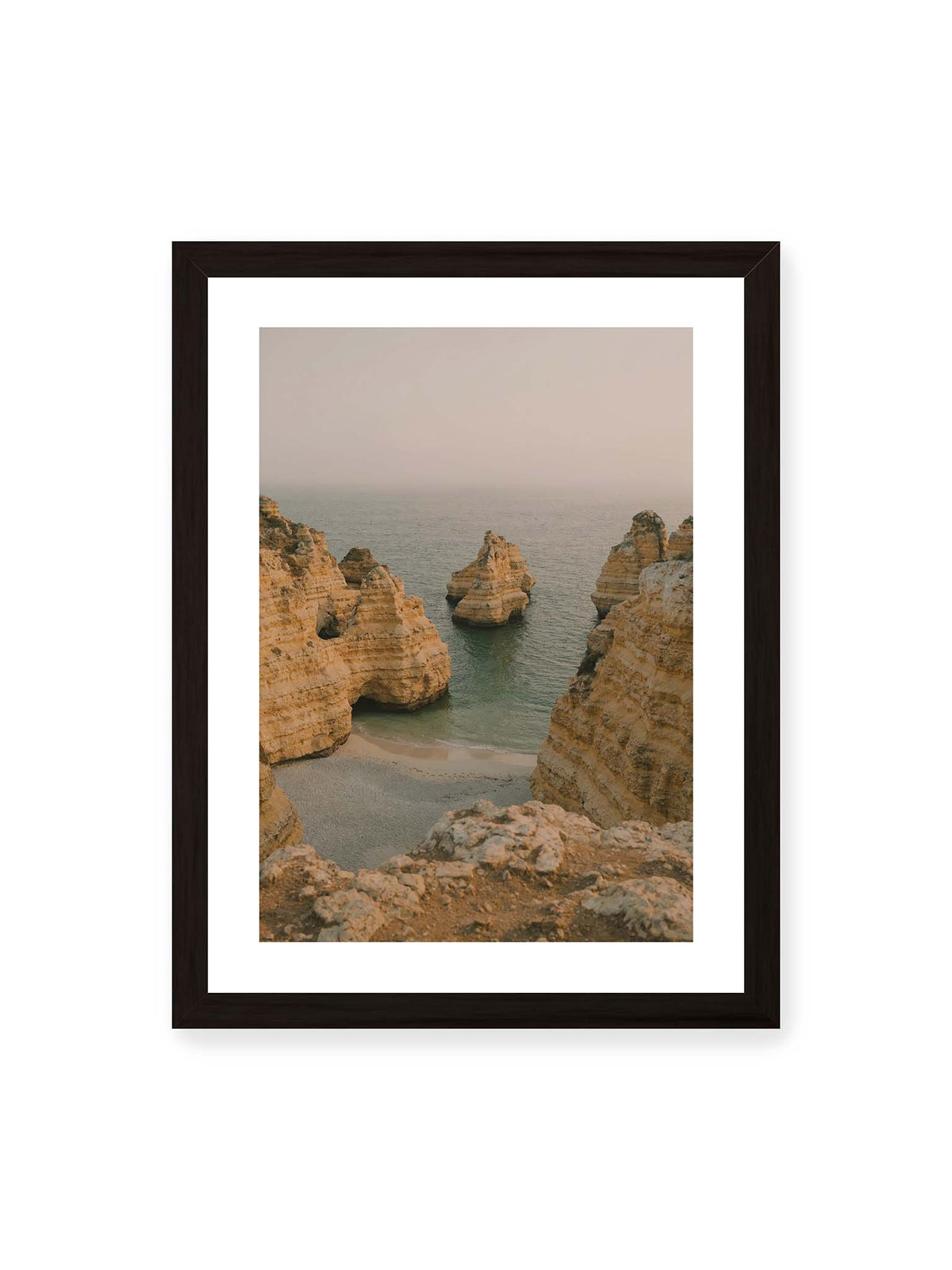 30x40 cm, weißer Galerie-Rand, schwarzer Rahmen – Schichtartige Felsformationen umgeben eine kleine Bucht mit ruhigem Wasser und schmalem Sandstrand.