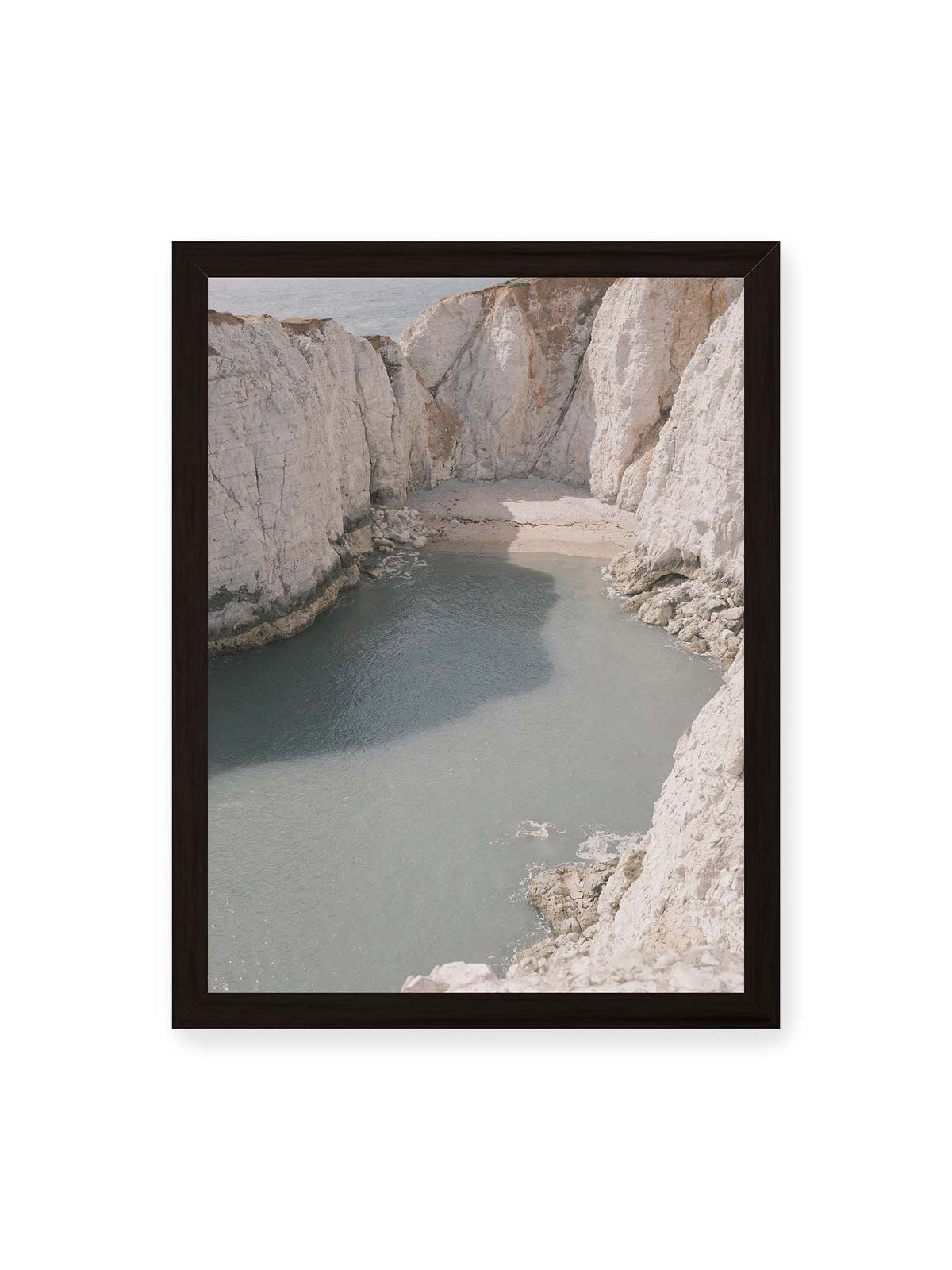 30x40 cm, schwarzer Rahmen – Helle steile Felswände umschließen eine kleine Bucht mit ruhigem Wasser und einem schmalen Strand.
