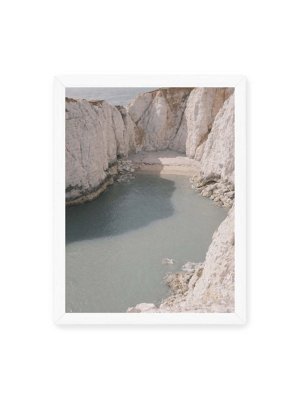 30x40 cm, weißer Rahmen – Helle steile Felswände umschließen eine kleine Bucht mit ruhigem Wasser und einem schmalen Strand.