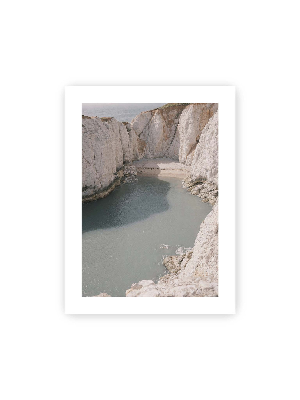 30x40 cm, weißer Galerie-Rand – Helle steile Felswände umschließen eine kleine Bucht mit ruhigem Wasser und einem schmalen Strand.