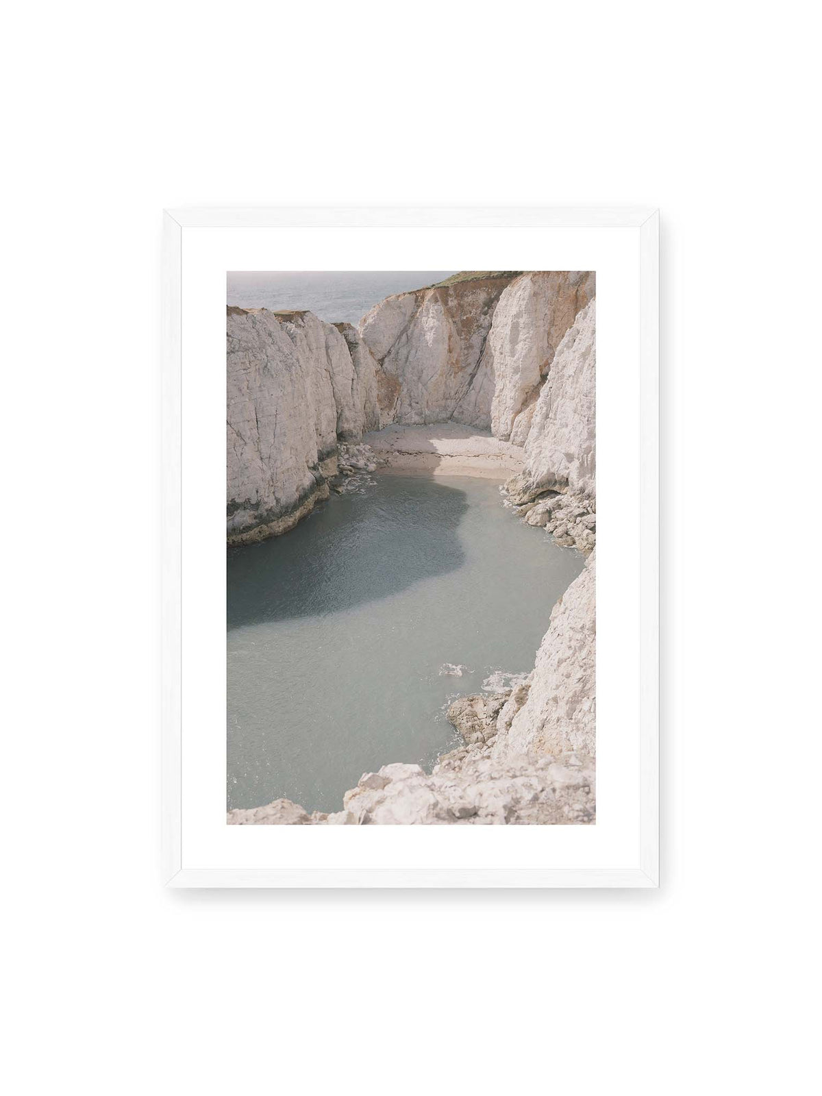 50x70 cm, weißer Galerie-Rand, weißer Rahmen – Helle steile Felswände umschließen eine kleine Bucht mit ruhigem Wasser und einem schmalen Strand.