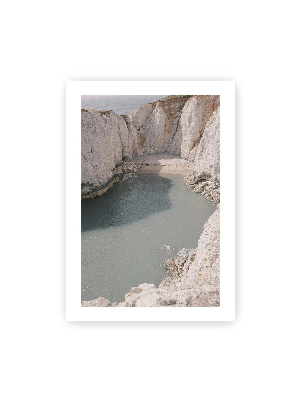 70x100 cm, weißer Galerie-Rand – Helle steile Felswände umschließen eine kleine Bucht mit ruhigem Wasser und einem schmalen Strand.
