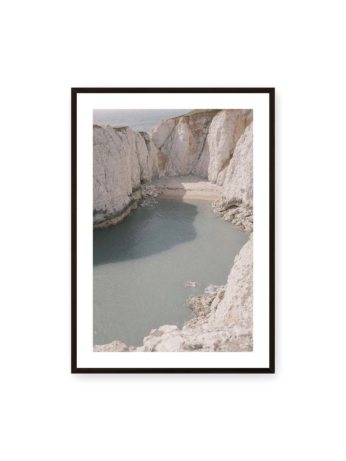 70x100 cm, weißer Galerie-Rand, schwarzer Rahmen – Helle steile Felswände umschließen eine kleine Bucht mit ruhigem Wasser und einem schmalen Strand.