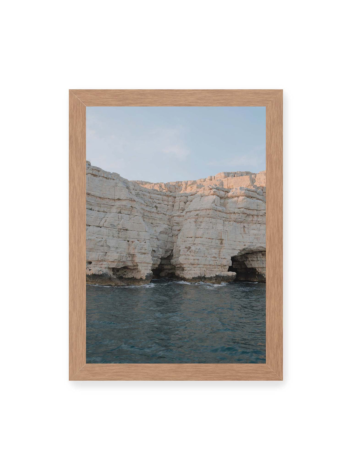 21x30 cm, Eichenrahmen – Helle geschichtete Felswand mit dunklen Grotten über bewegtem blauem Meer und blassem Himmel.