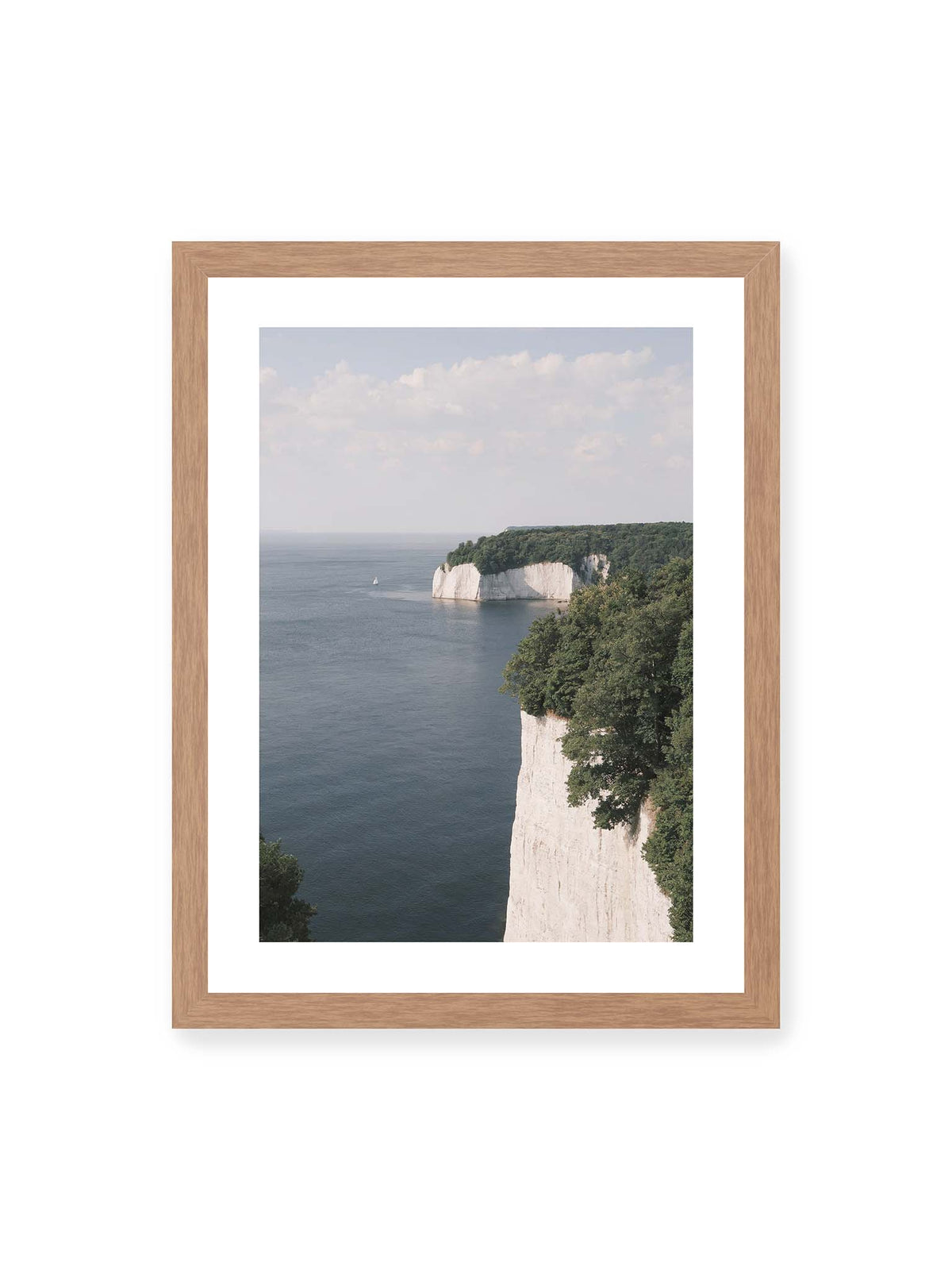 30x40 cm, weißer Galerie-Rand, Eichenrahmen – Helle Steilklippen mit grünen Baumkronen über ruhigem blauem Meer und einem kleinen Segelboot.