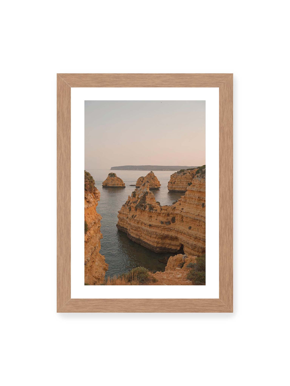 21x30 cm, weißer Galerie-Rand, Eichenrahmen – Warm getönte, geschichtete Felsformationen ragen zwischen steilen Küstenwänden aus ruhigem Meer.