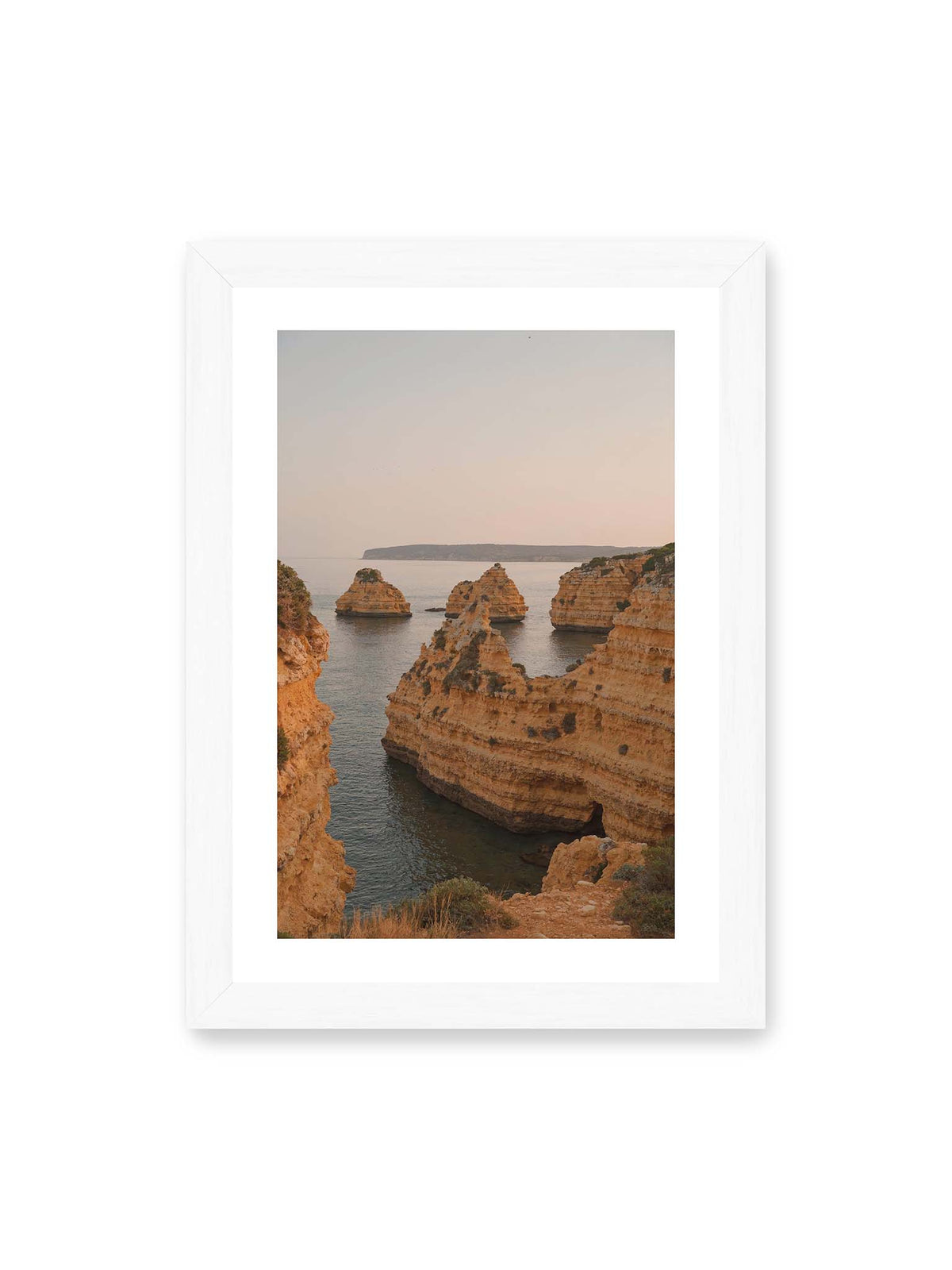 21x30 cm, weißer Galerie-Rand, weißer Rahmen – Warm getönte, geschichtete Felsformationen ragen zwischen steilen Küstenwänden aus ruhigem Meer.