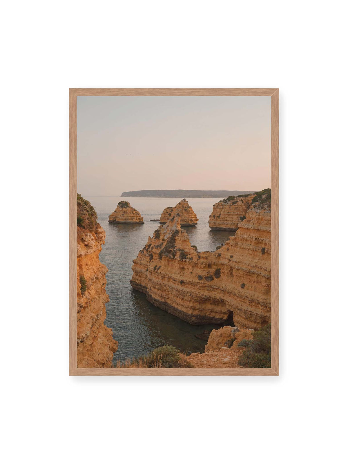 50x70 cm, Eichenrahmen – Warm getönte, geschichtete Felsformationen ragen zwischen steilen Küstenwänden aus ruhigem Meer.