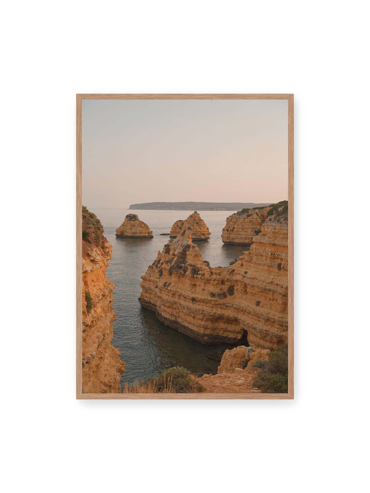 70x100 cm, Eichenrahmen – Warm getönte, geschichtete Felsformationen ragen zwischen steilen Küstenwänden aus ruhigem Meer.