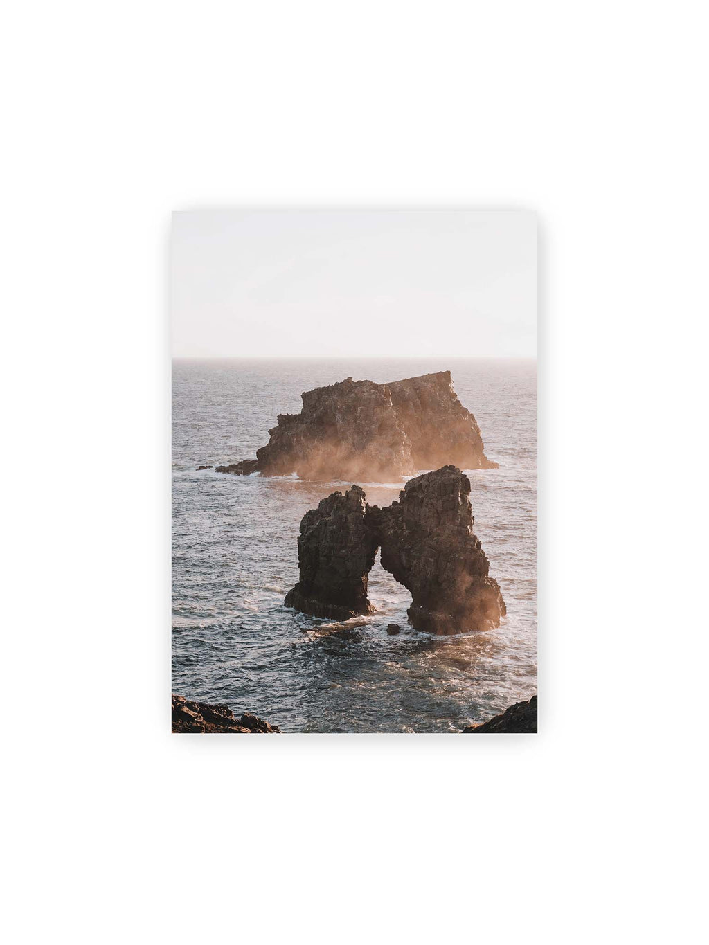 21x30 cm – Dunkler Felsbogen und massive Felsformation im bewegten Meer, umgeben von heller Gischt und warmem Licht.