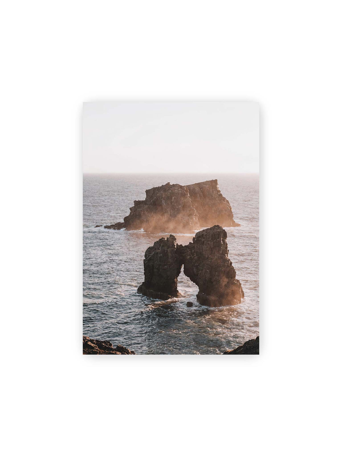 21x30 cm – Dunkler Felsbogen und massive Felsformation im bewegten Meer, umgeben von heller Gischt und warmem Licht.