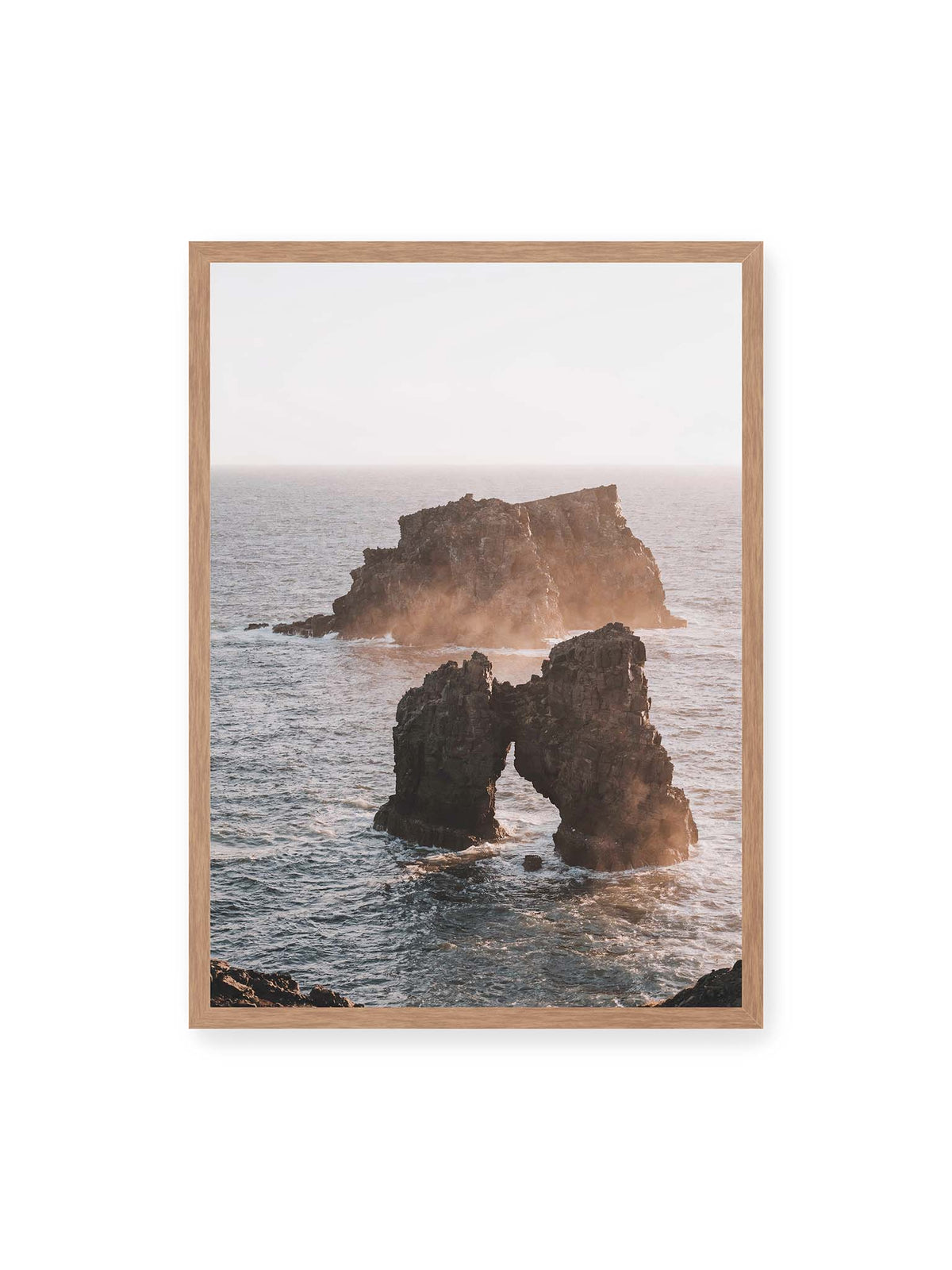 50x70 cm, Eichenrahmen – Dunkler Felsbogen und massive Felsformation im bewegten Meer, umgeben von heller Gischt und warmem Licht.