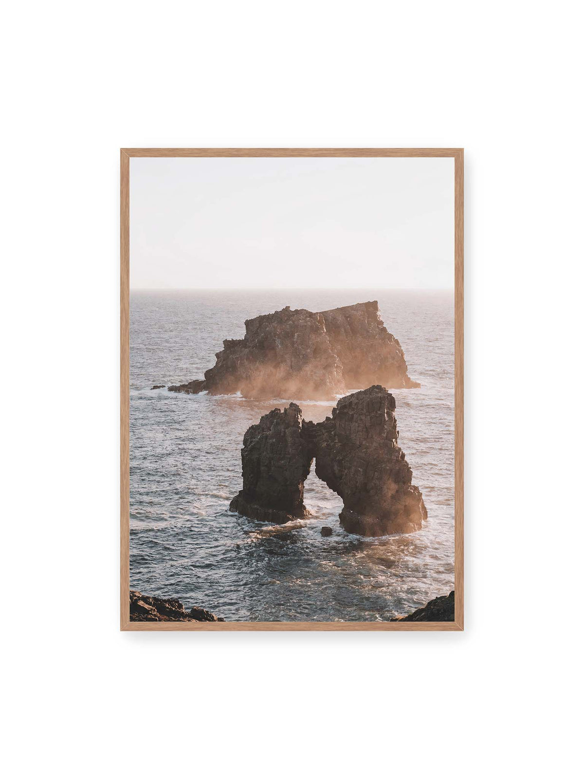 70x100 cm, Eichenrahmen – Dunkler Felsbogen und massive Felsformation im bewegten Meer, umgeben von heller Gischt und warmem Licht.