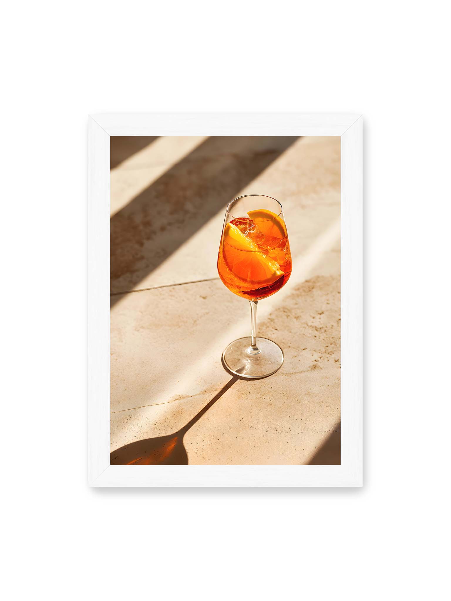 21x30 cm, weißer Rahmen – Aperitifglas mit orangefarbenem Drink und Orangenscheiben, Sonnenlicht und langer Schatten auf hellem Stein.