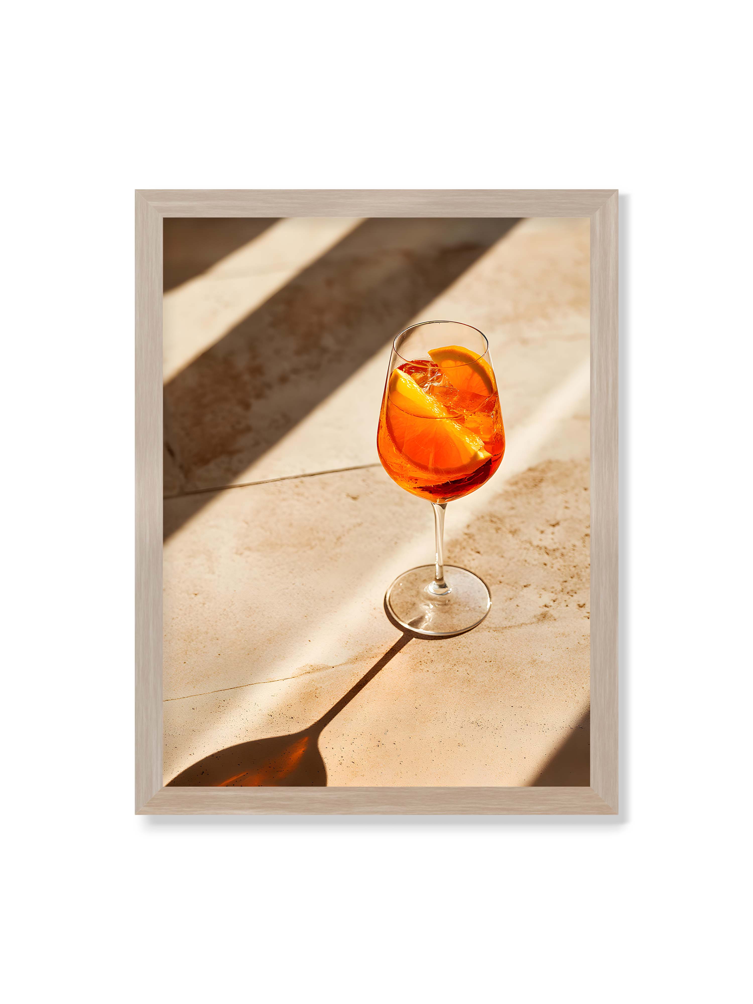 30x40 cm ohne Galerie-Rand im Eichenrahmen – Aperitifglas mit orangefarbenem Drink und Orangenscheiben, Sonnenlicht und langer Schatten auf hellem Stein.