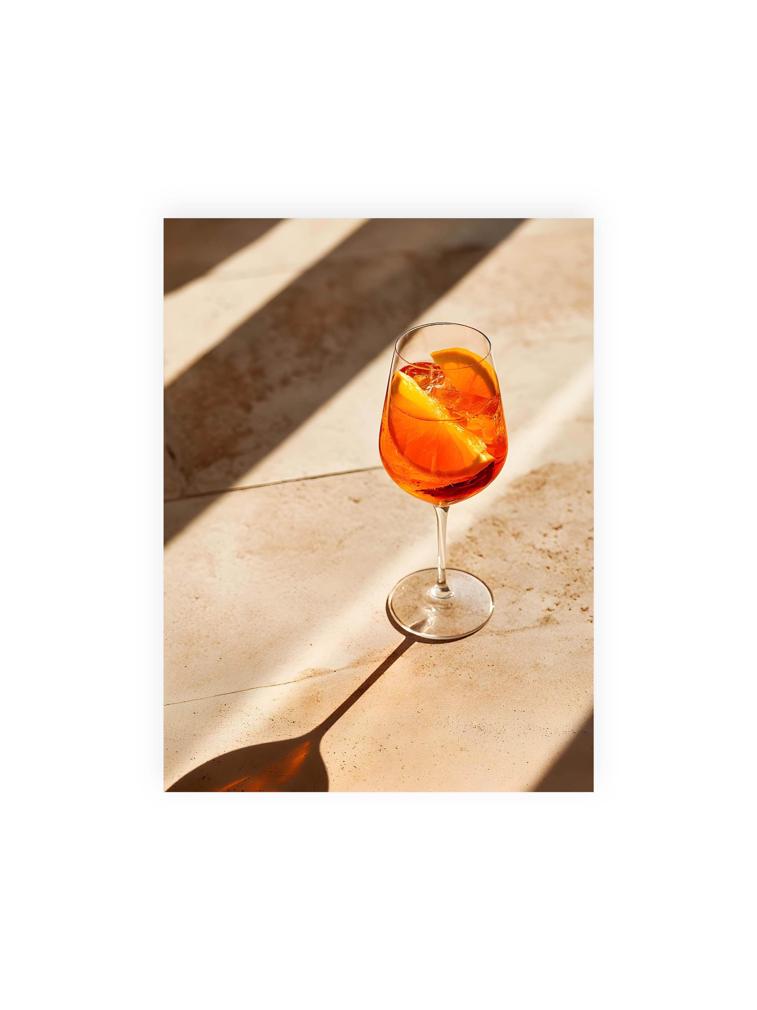 30x40 cm ohne Galerie-Rand ohne Rahmen – Aperitifglas mit orangefarbenem Drink und Orangenscheiben, Sonnenlicht und langer Schatten auf hellem Stein.