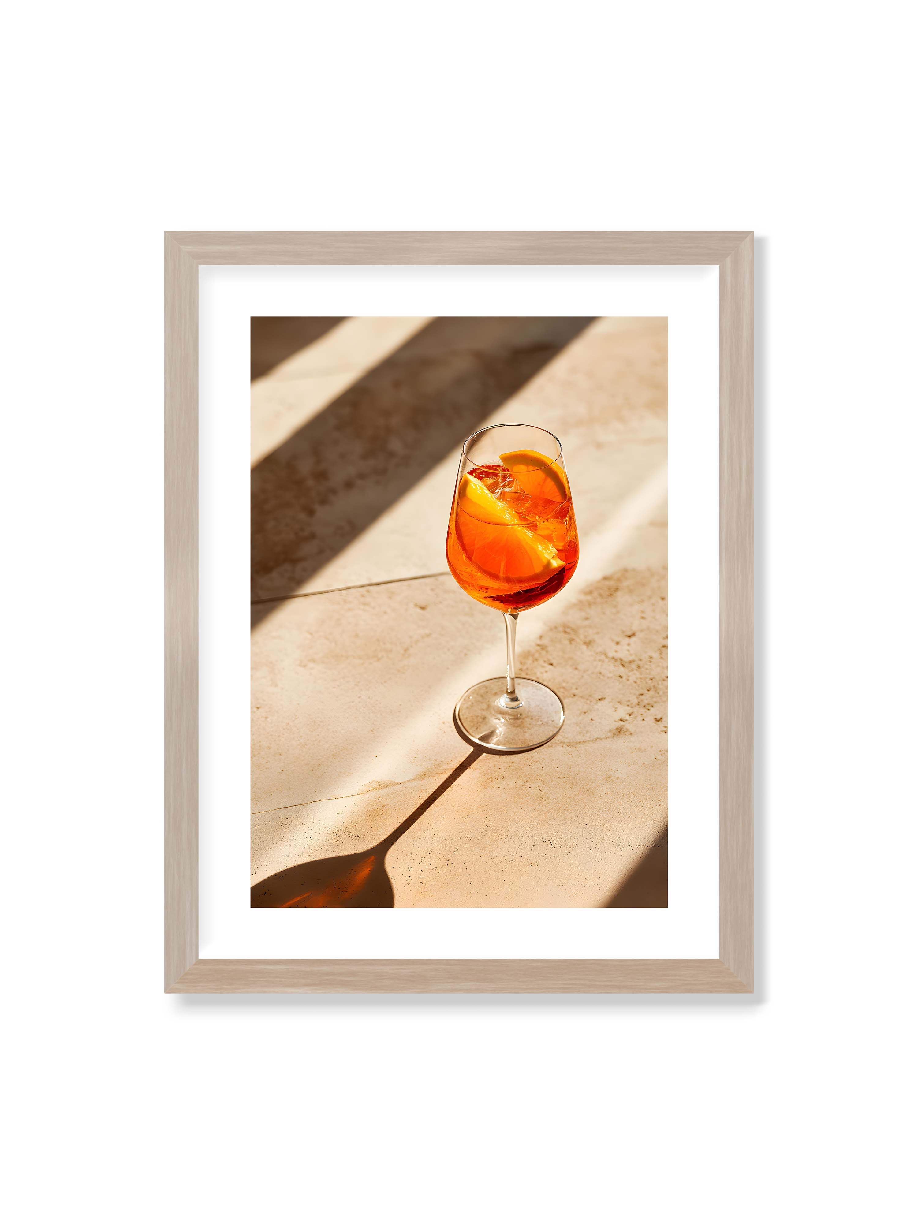 30x40 cm mit weißem Galerie-Rand im Eichenrahmen – Aperitifglas mit orangefarbenem Drink und Orangenscheiben, Sonnenlicht und langer Schatten auf hellem Stein.