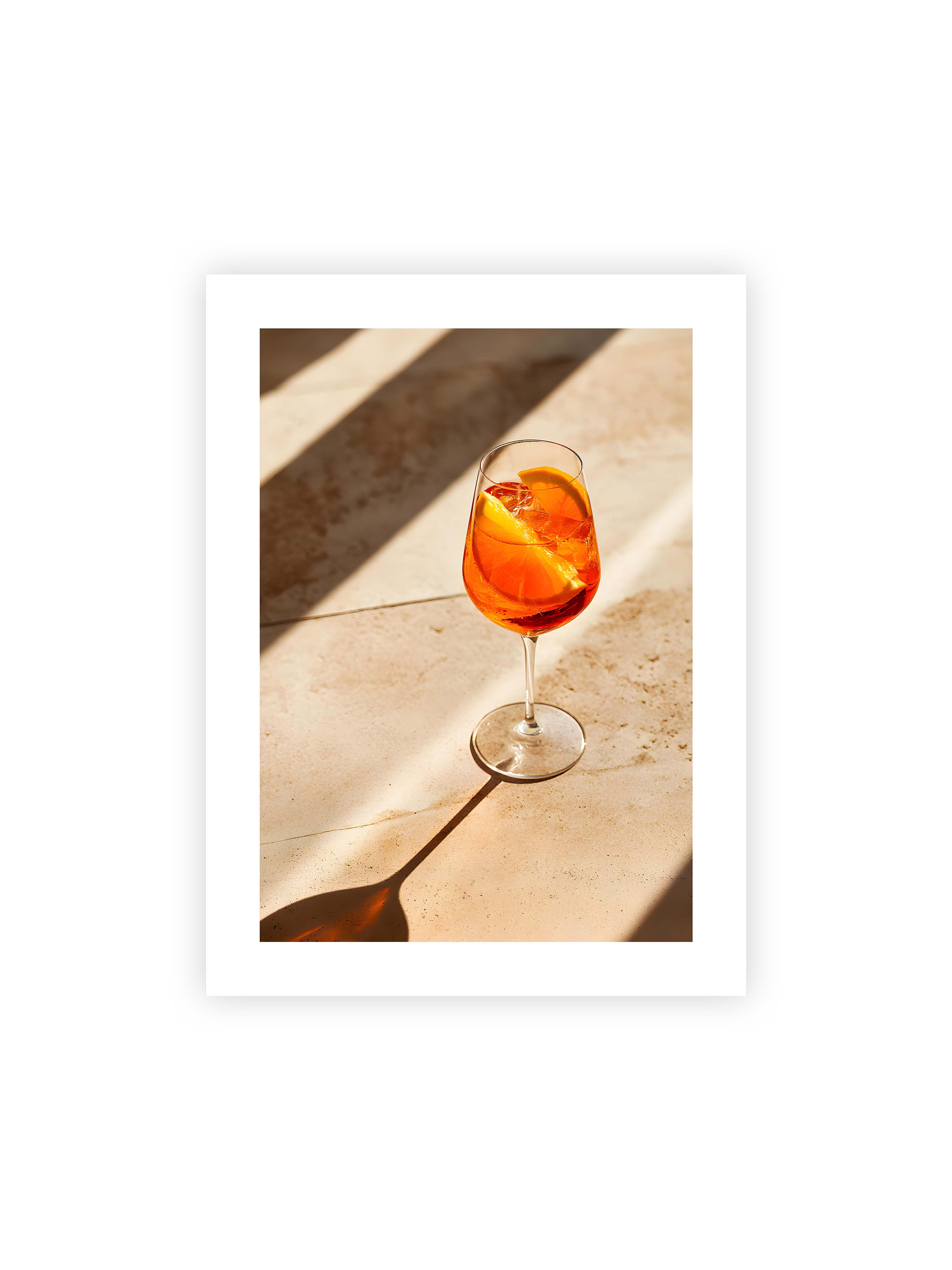 30x40 cm mit weißem Galerie-Rand ohne Rahmen – Aperitifglas mit orangefarbenem Drink und Orangenscheiben, Sonnenlicht und langer Schatten auf hellem Stein.