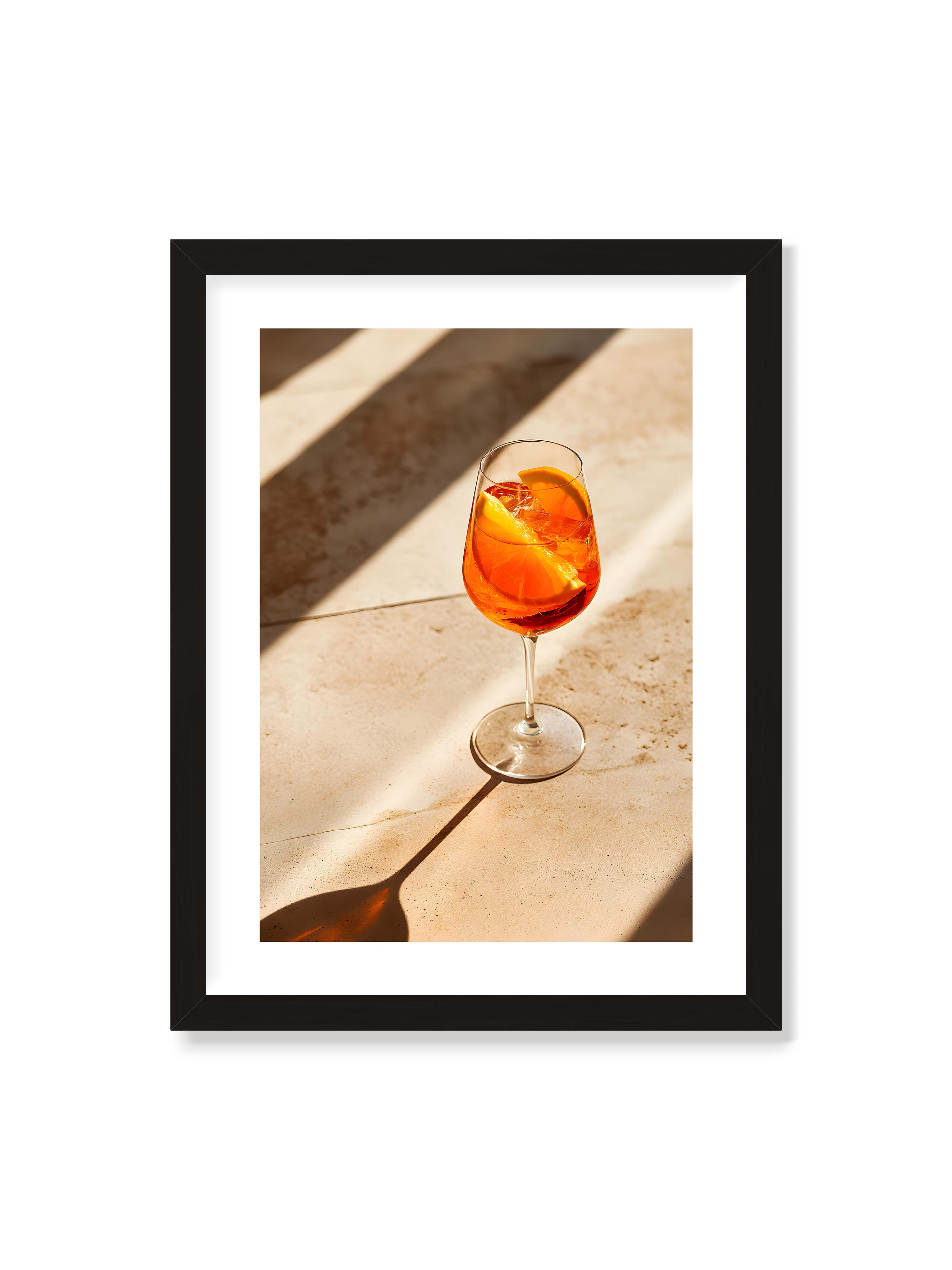 30x40 cm mit weißem Galerie-Rand mit schwarzem Rahmen – Aperitifglas mit orangefarbenem Drink und Orangenscheiben, Sonnenlicht und langer Schatten auf hellem Stein.