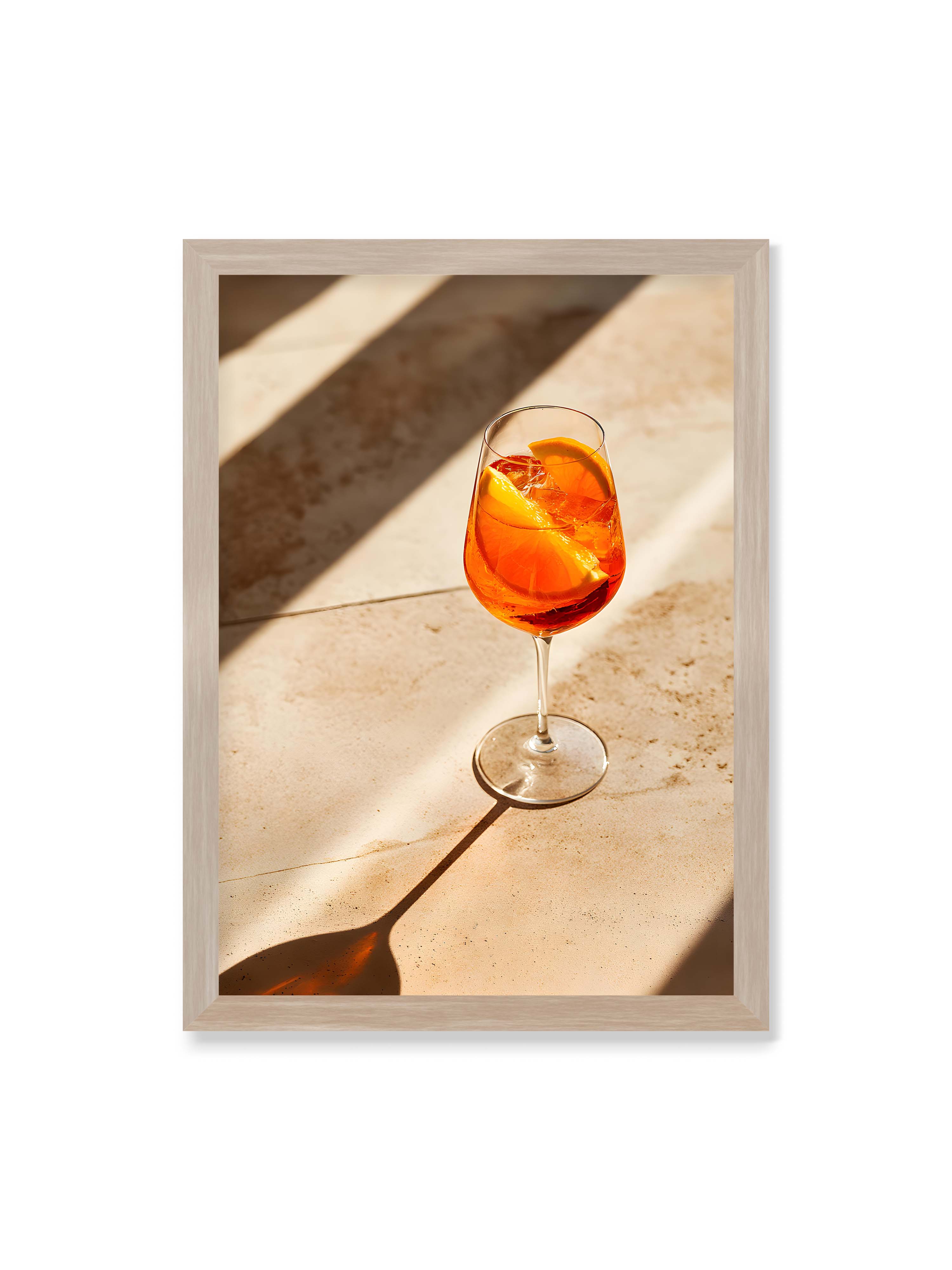 50x70 cm ohne Galerie-Rand im Eichenrahmen – Aperitifglas mit orangefarbenem Drink und Orangenscheiben, Sonnenlicht und langer Schatten auf hellem Stein.