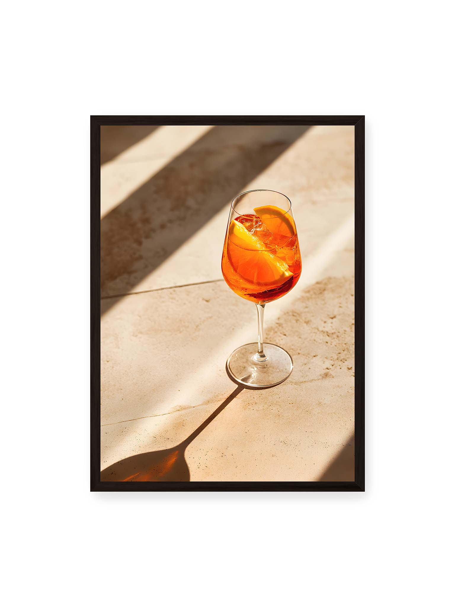 50x70 cm, schwarzer Rahmen – Aperitifglas mit orangefarbenem Drink und Orangenscheiben, Sonnenlicht und langer Schatten auf hellem Stein.