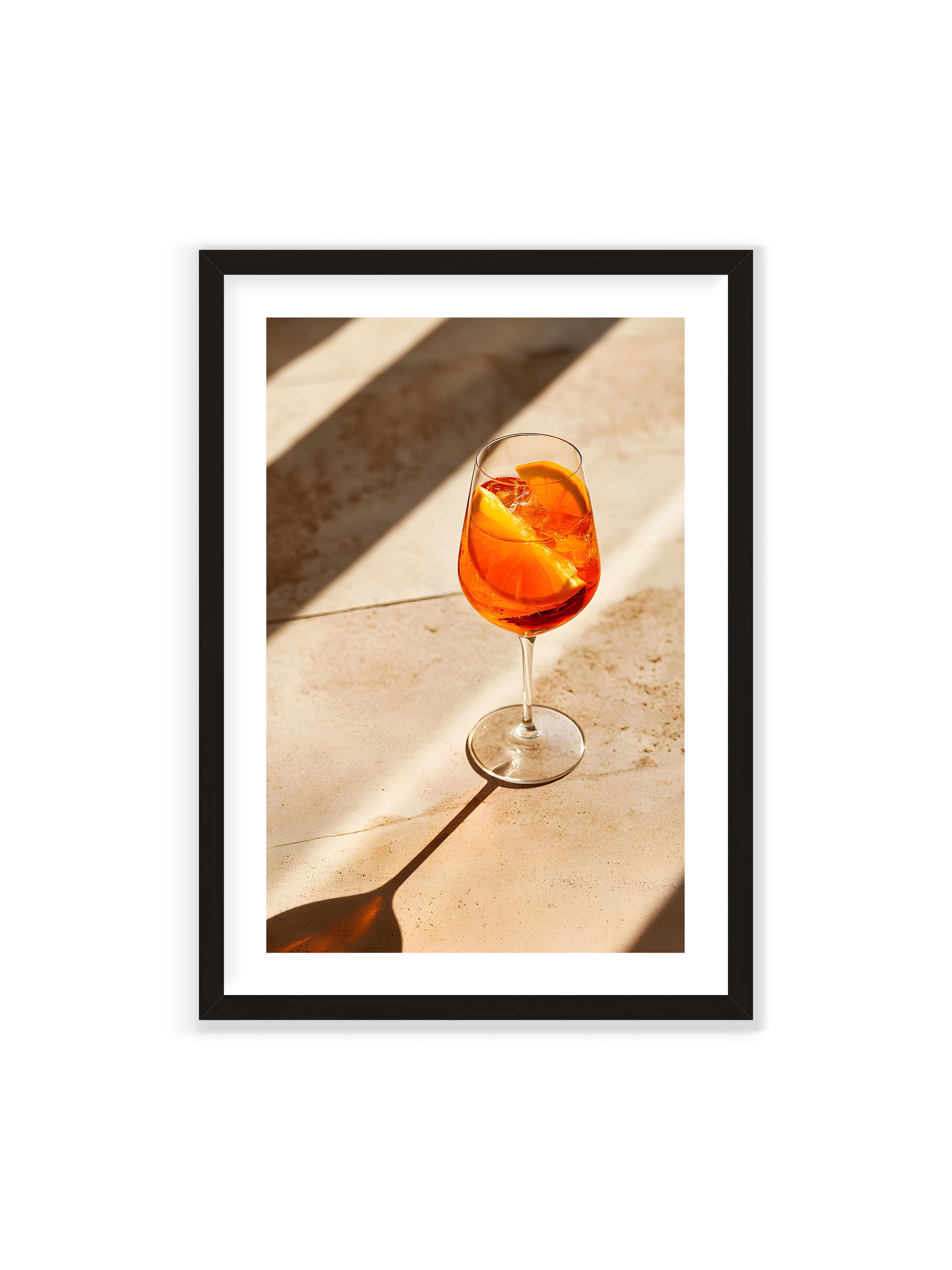 70x100 cm mit weißem Galerie-Rand mit schwarzem Rahmen – Aperitifglas mit orangefarbenem Drink und Orangenscheiben, Sonnenlicht und langer Schatten auf hellem Stein.