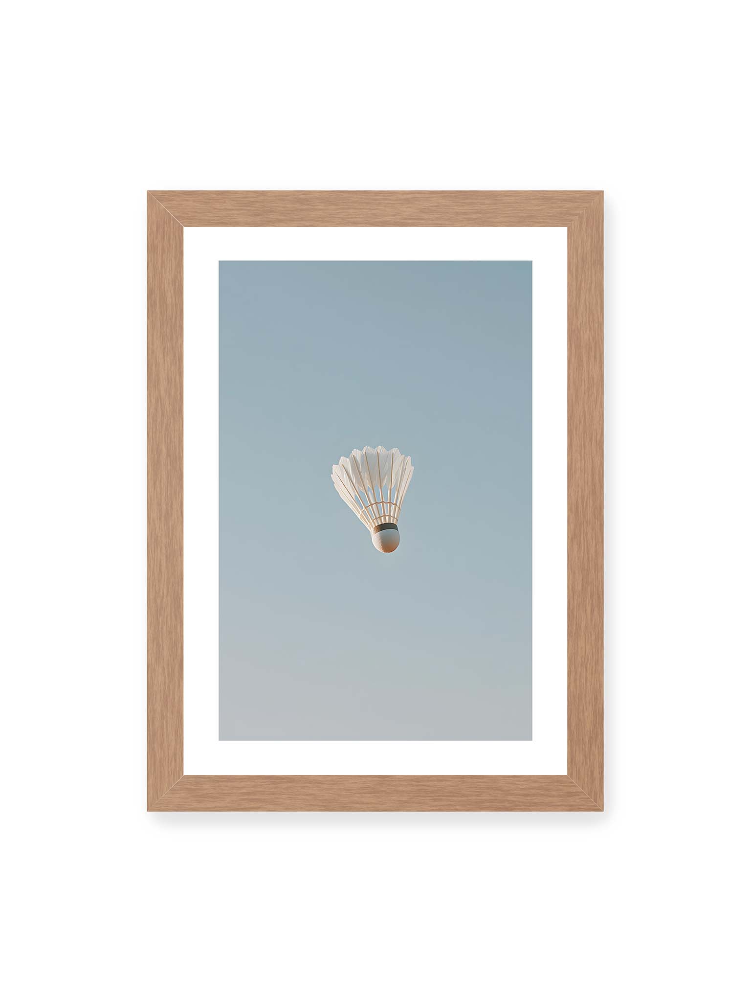 21x30 cm, weißer Galerie-Rand, Eichenrahmen – Weißer Federball schwebt zentriert vor hellblauem Himmel, minimalistische Komposition mit viel Freiraum.