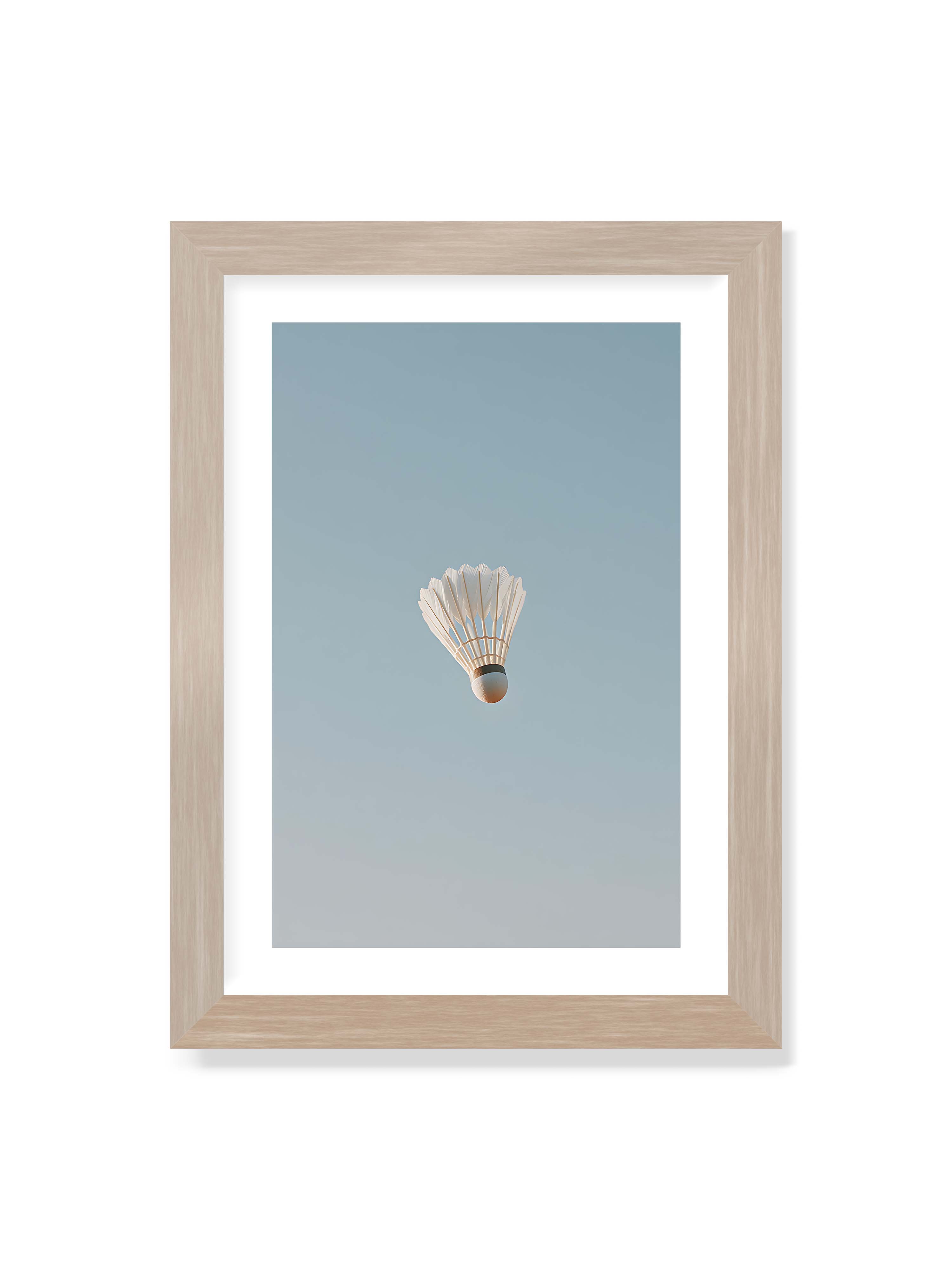 21x30 cm mit weißem Galerie-Rand im Eichenrahmen – Weißer Federball schwebt zentriert vor hellblauem Himmel, minimalistische Komposition mit viel Freiraum.
