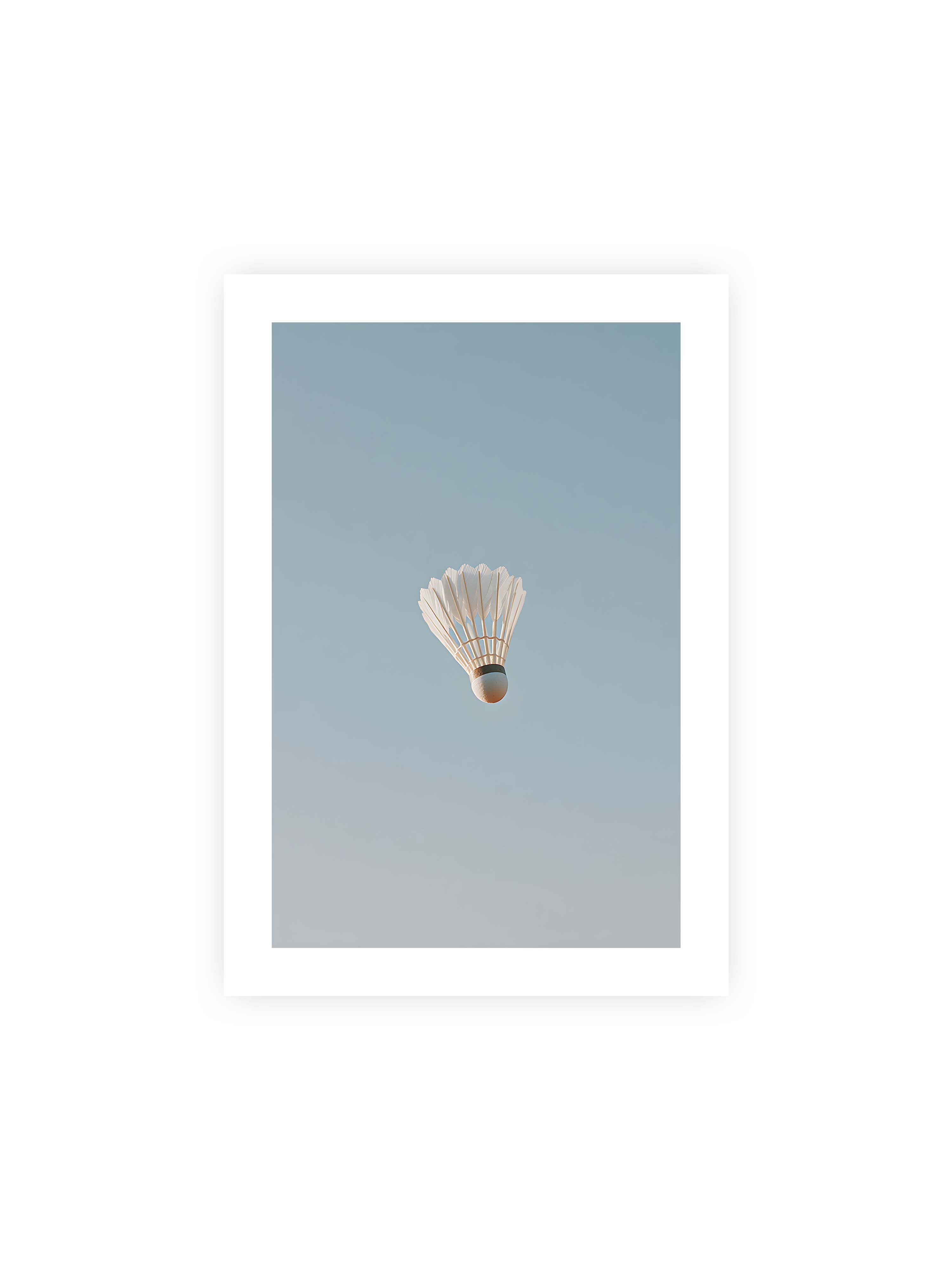 21x30 cm mit weißem Galerie-Rand ohne Rahmen – Weißer Federball schwebt zentriert vor hellblauem Himmel, minimalistische Komposition mit viel Freiraum.