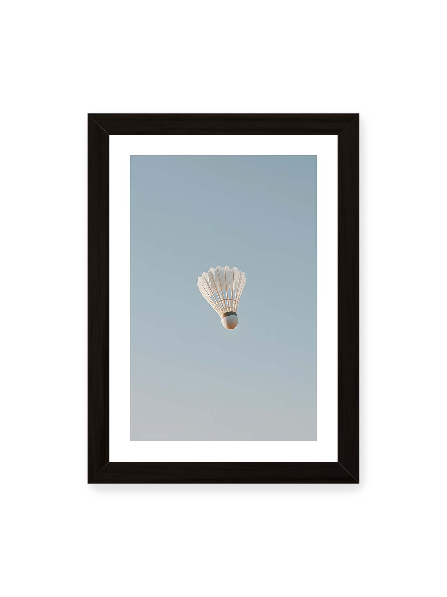21x30 cm, weißer Galerie-Rand, schwarzer Rahmen – Weißer Federball schwebt zentriert vor hellblauem Himmel, minimalistische Komposition mit viel Freiraum.