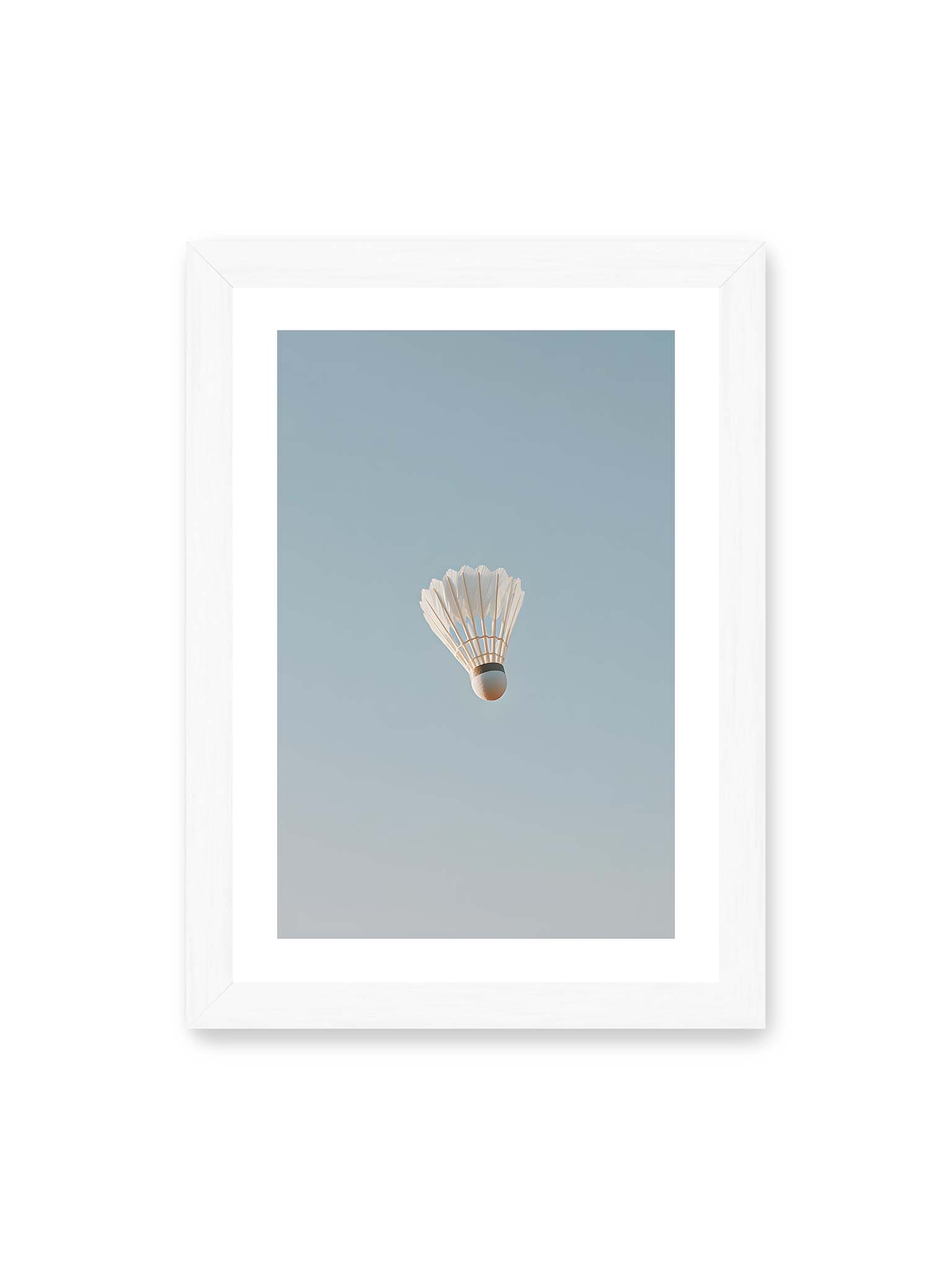 21x30 cm, weißer Galerie-Rand, weißer Rahmen – Weißer Federball schwebt zentriert vor hellblauem Himmel, minimalistische Komposition mit viel Freiraum.